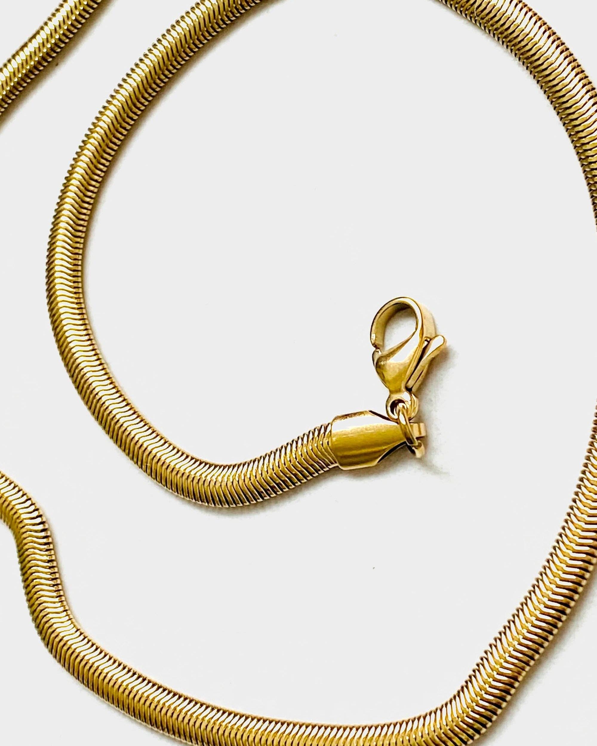 Close up on lobster clasp of 18k gold 15 inch to 17 inch herringbone necklace laid out in a swirl pattern on white background