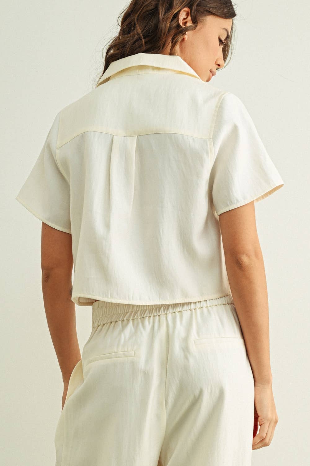 Woman wearing a cream-colored outfit with a plain background
