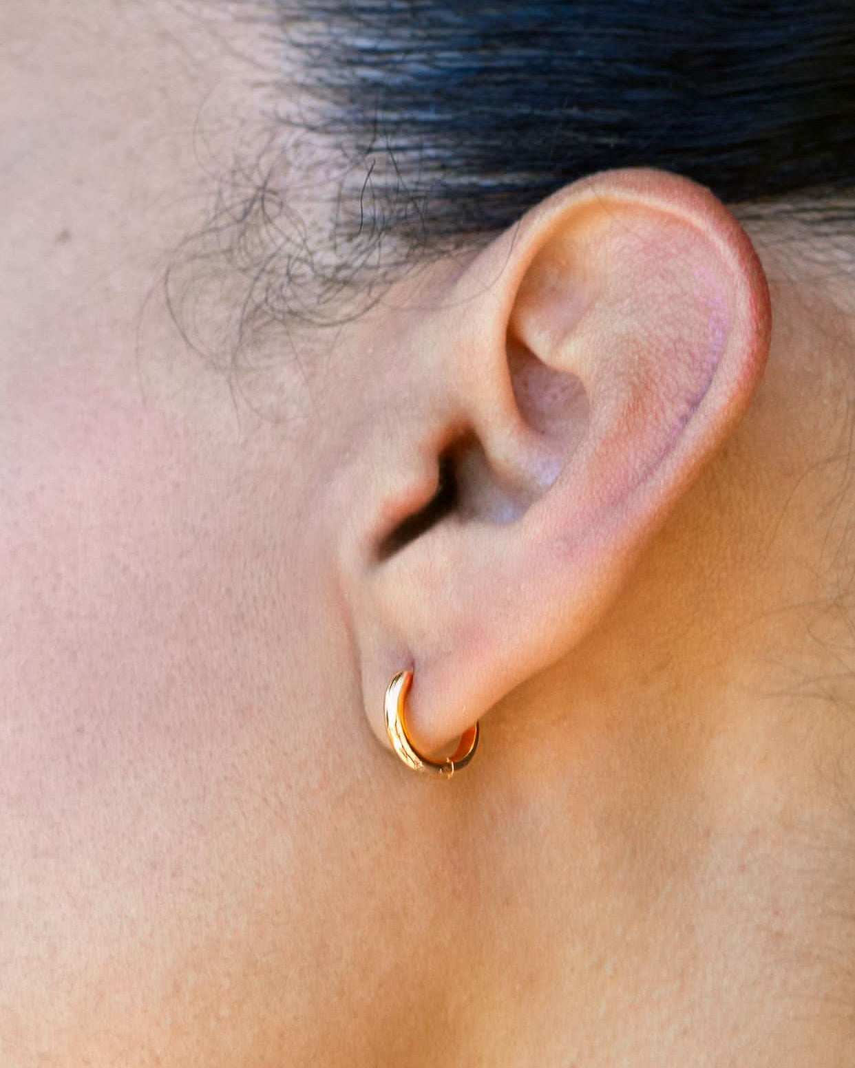 Woman wearing the everyday gold Huggies medium sized hoops