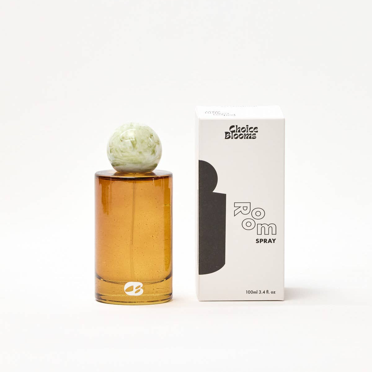 Amber glass perfume bottle with decorative cap next to its packaging on a white background