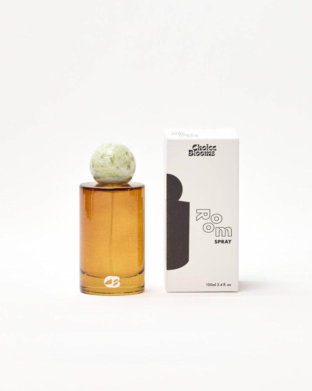 Amber glass perfume bottle with decorative cap next to its packaging on a white background