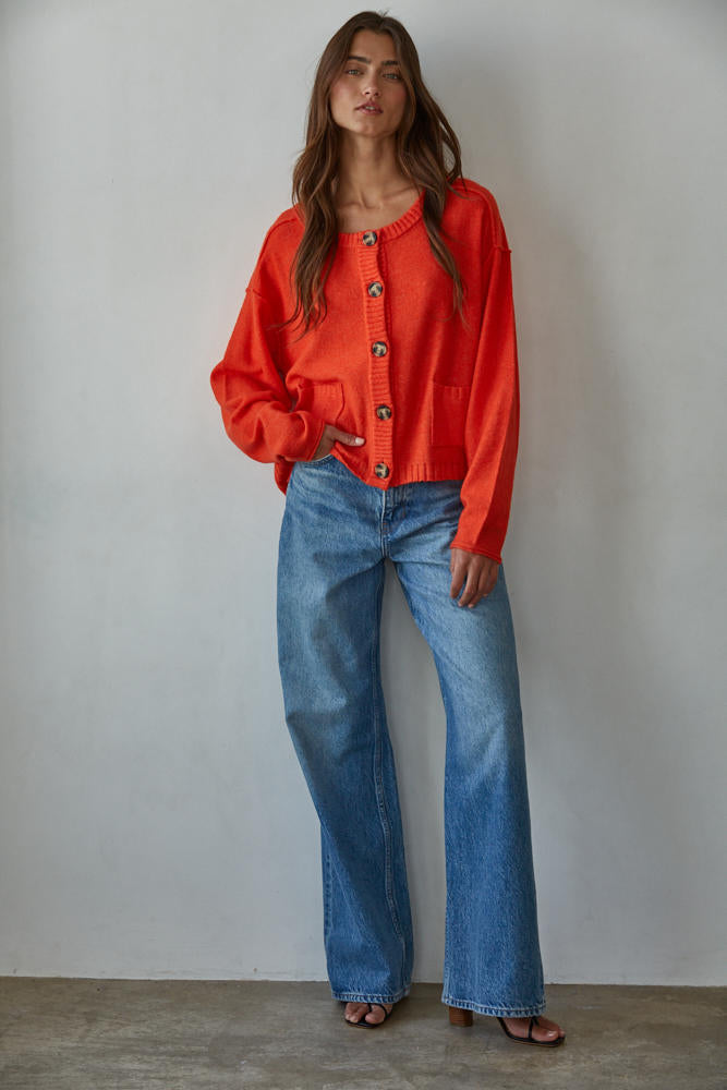 Woman wearing a Cloud Nine Cardigan Top red and blue jeans