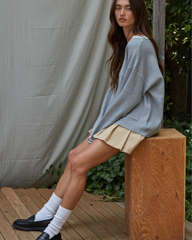 Woman sitting on a wooden block wearing a light blue sweater