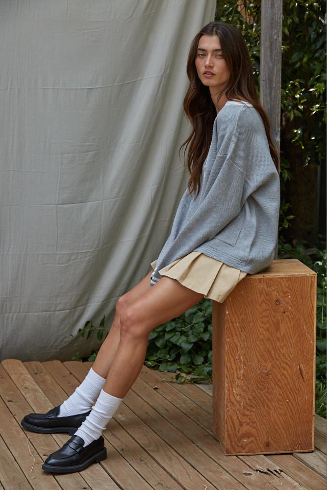 Woman sitting on a wooden block wearing a light blue sweater