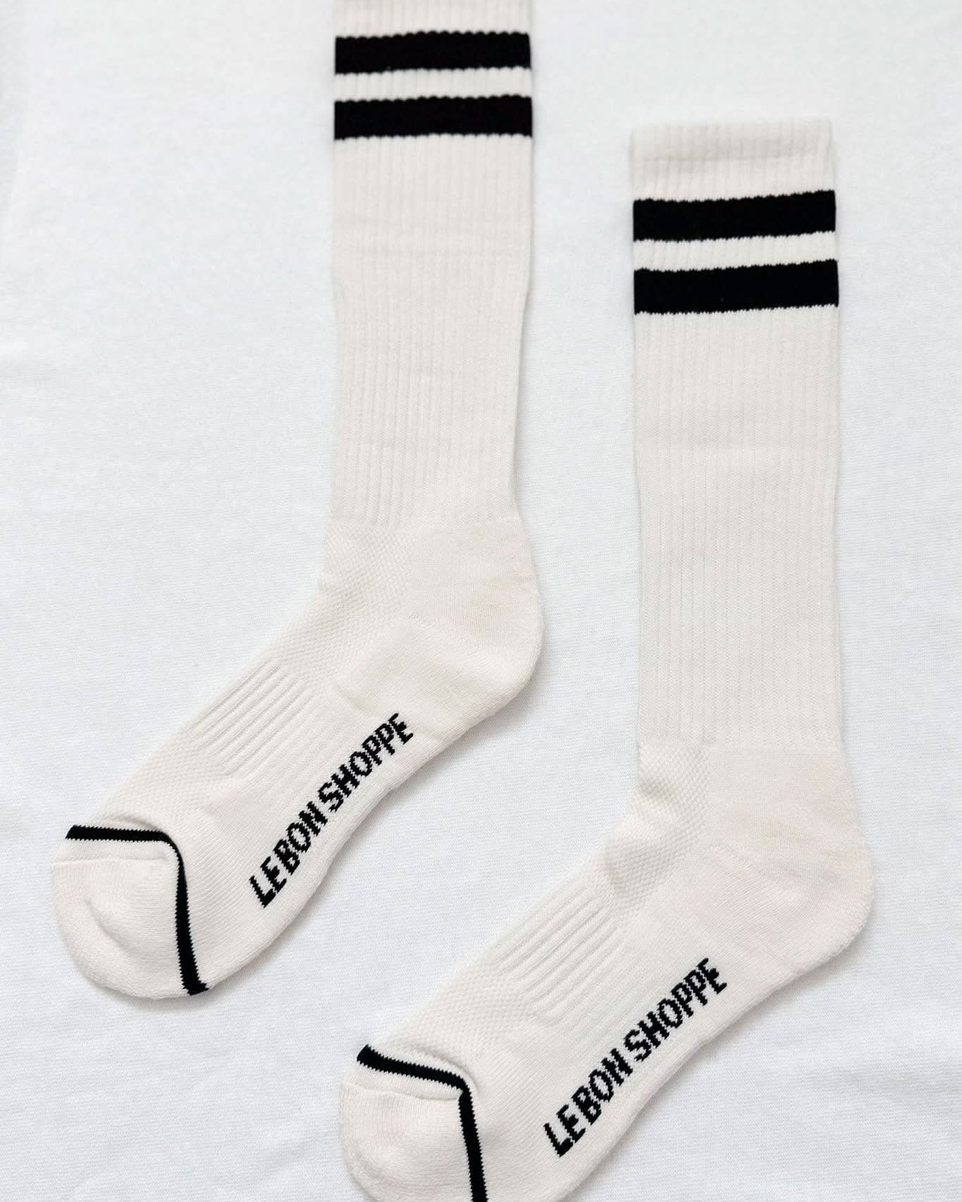 White socks with black stripes and 'Lebon Shoppe' branding on a light gray background