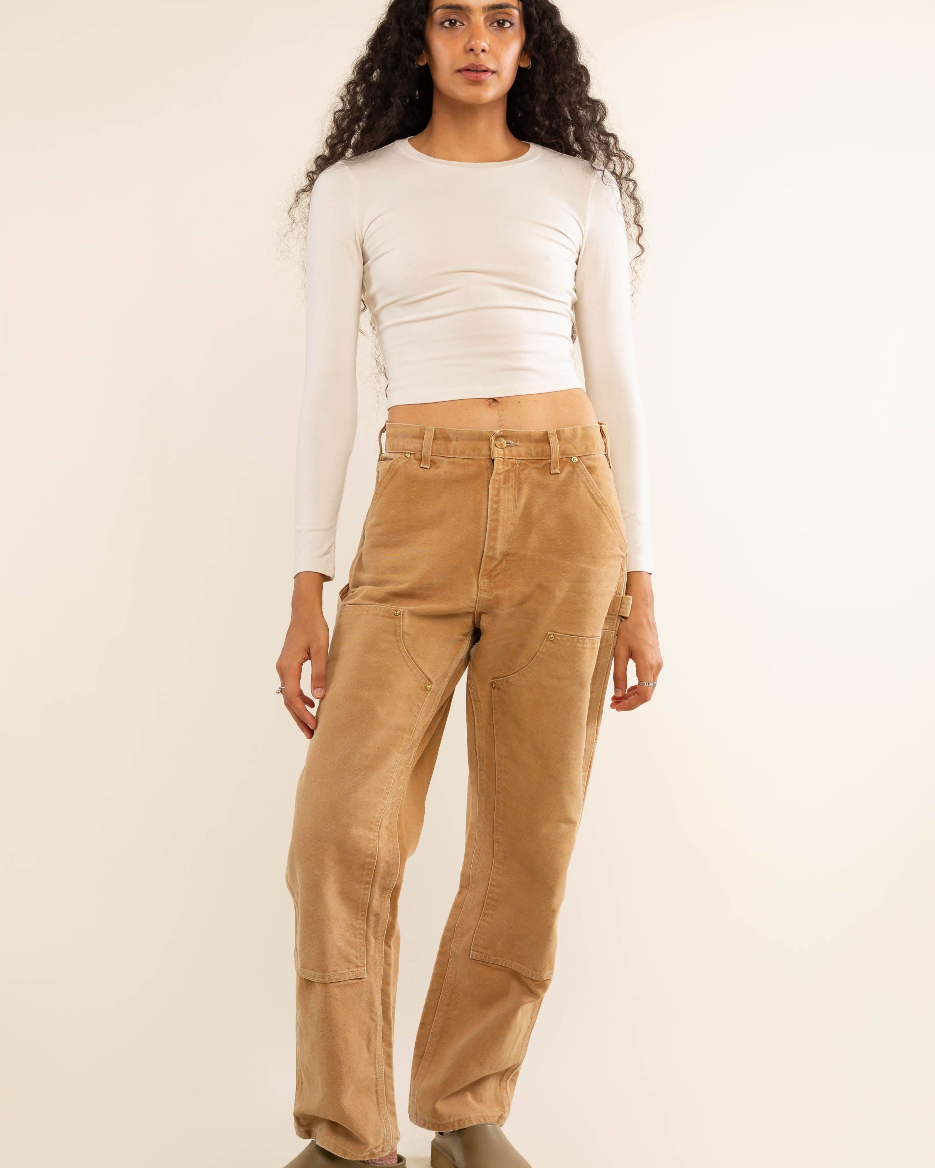 Woman wearing white, long sleeve, tight, crew neck, top with khaki jeans