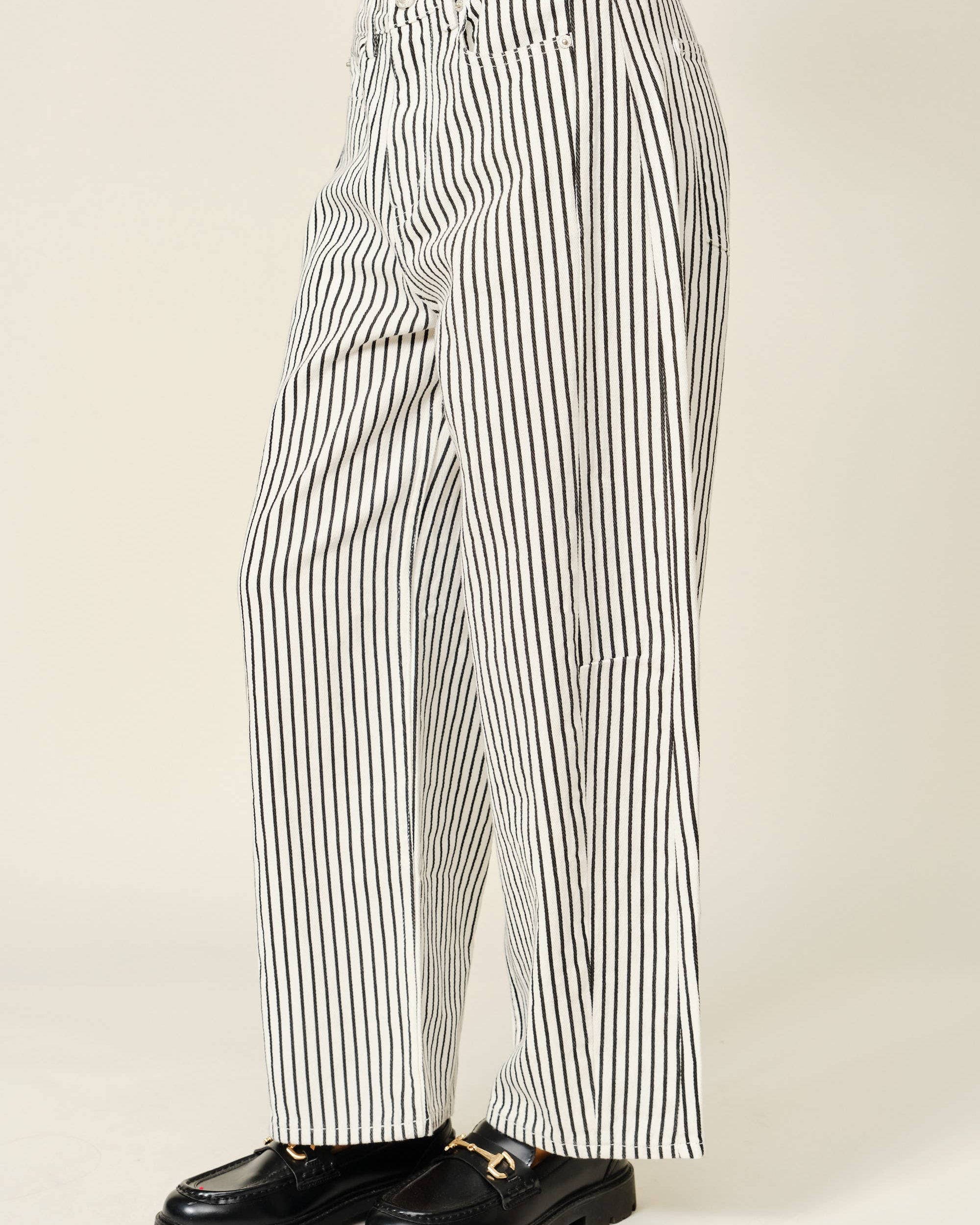 Black and white striped pants worn by a person on a beige background