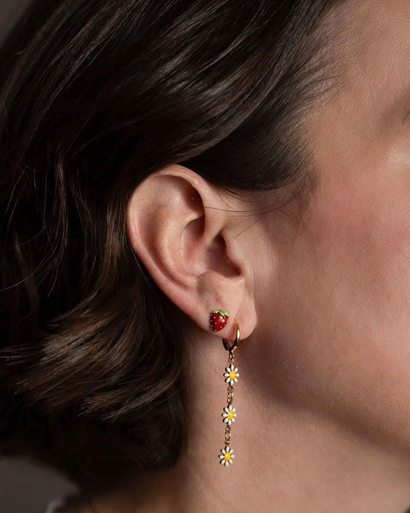 Woman wearing strawberry stud earrings in second piercing with long daisy earrings in first piercing