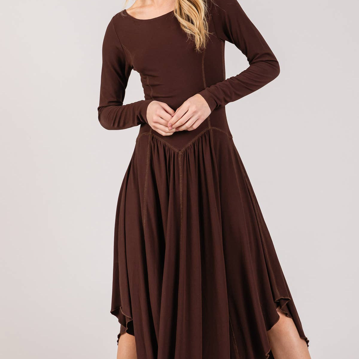 Woman wearing a brown dress with long sleeves on a white background
