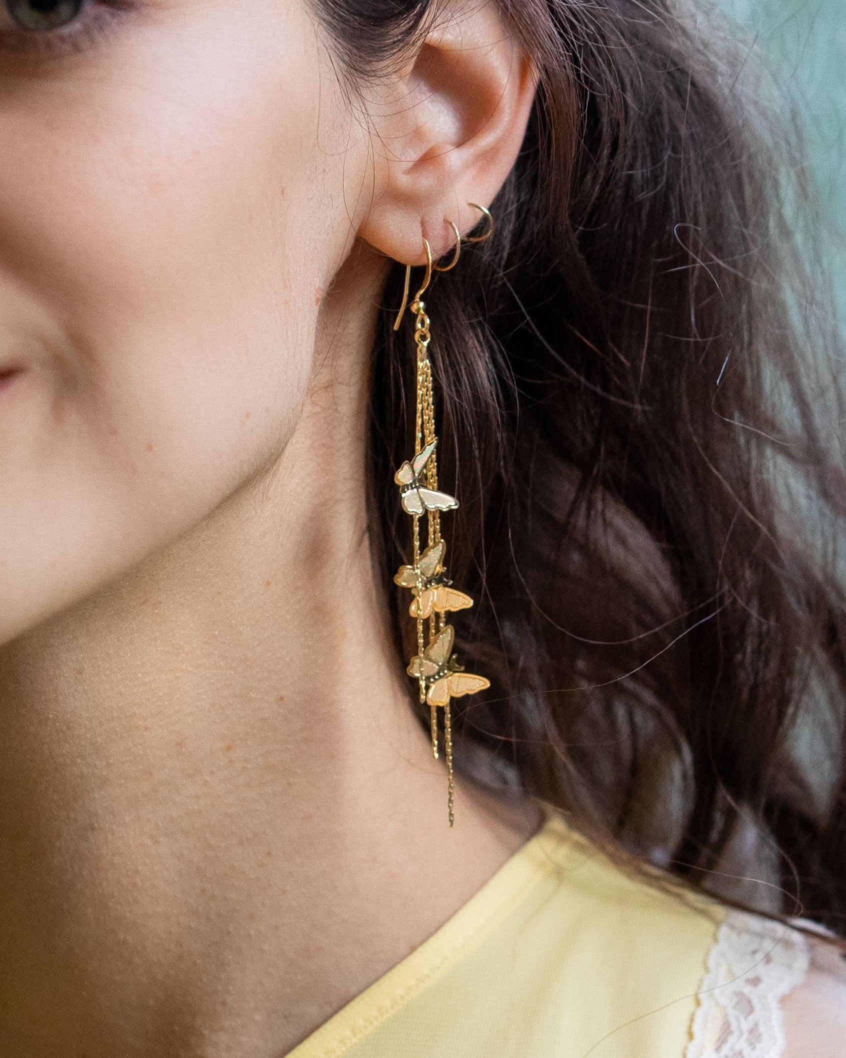 woman wearing gold butterflies dripping chain earrings