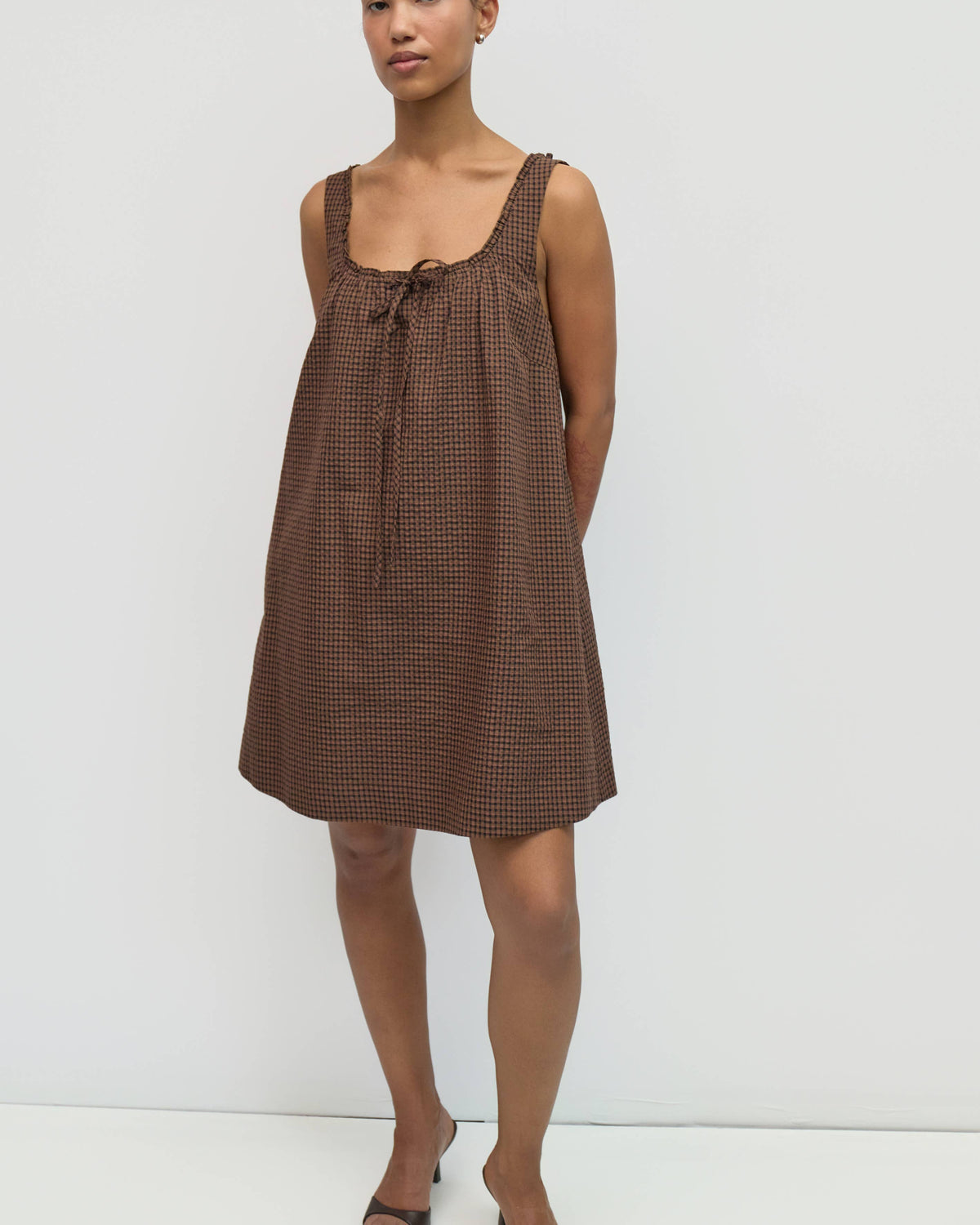 Woman wearing a brown checkered dress against a white background