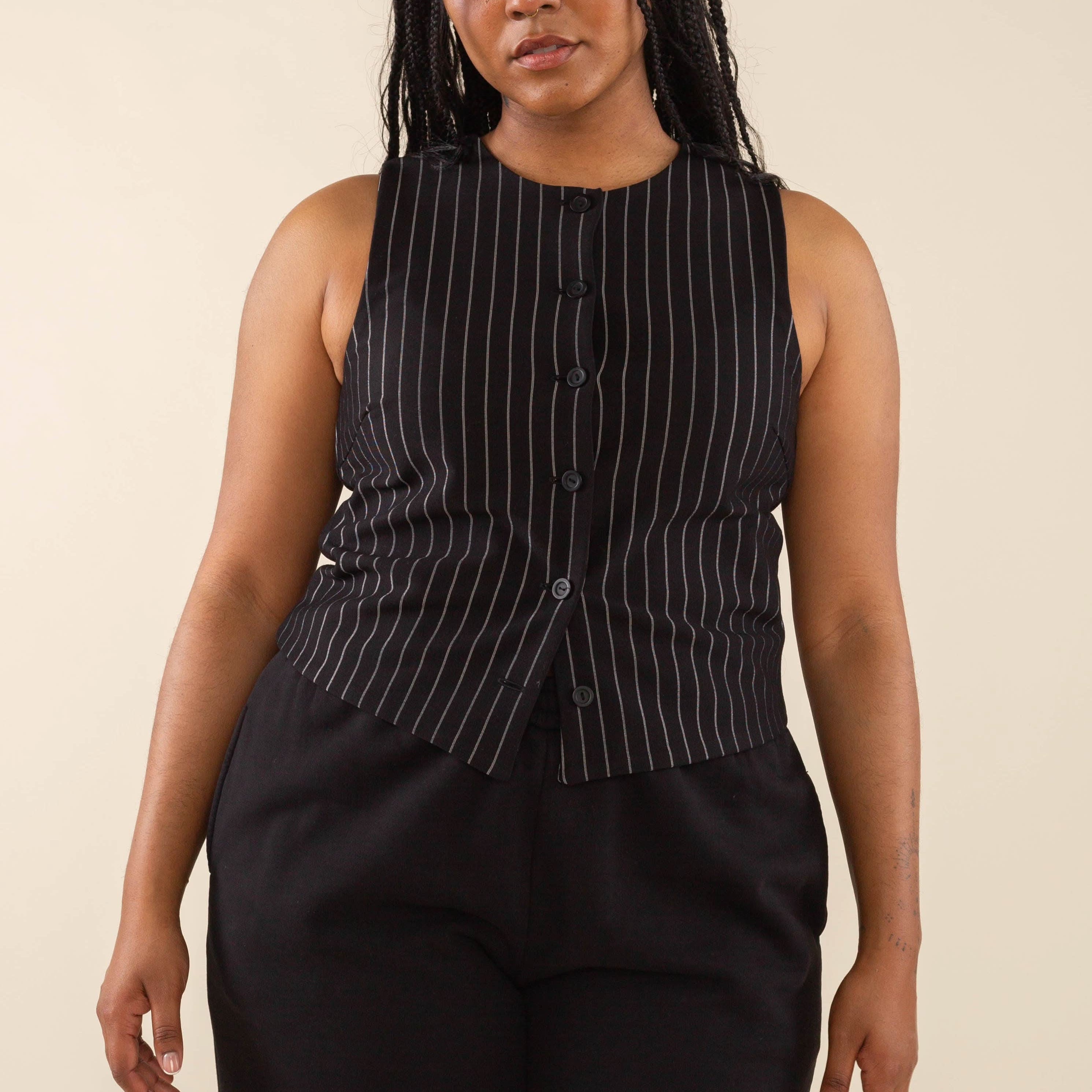 Woman wearing black high neck vest with cream pinstripes. Vest has black buttons all the way down