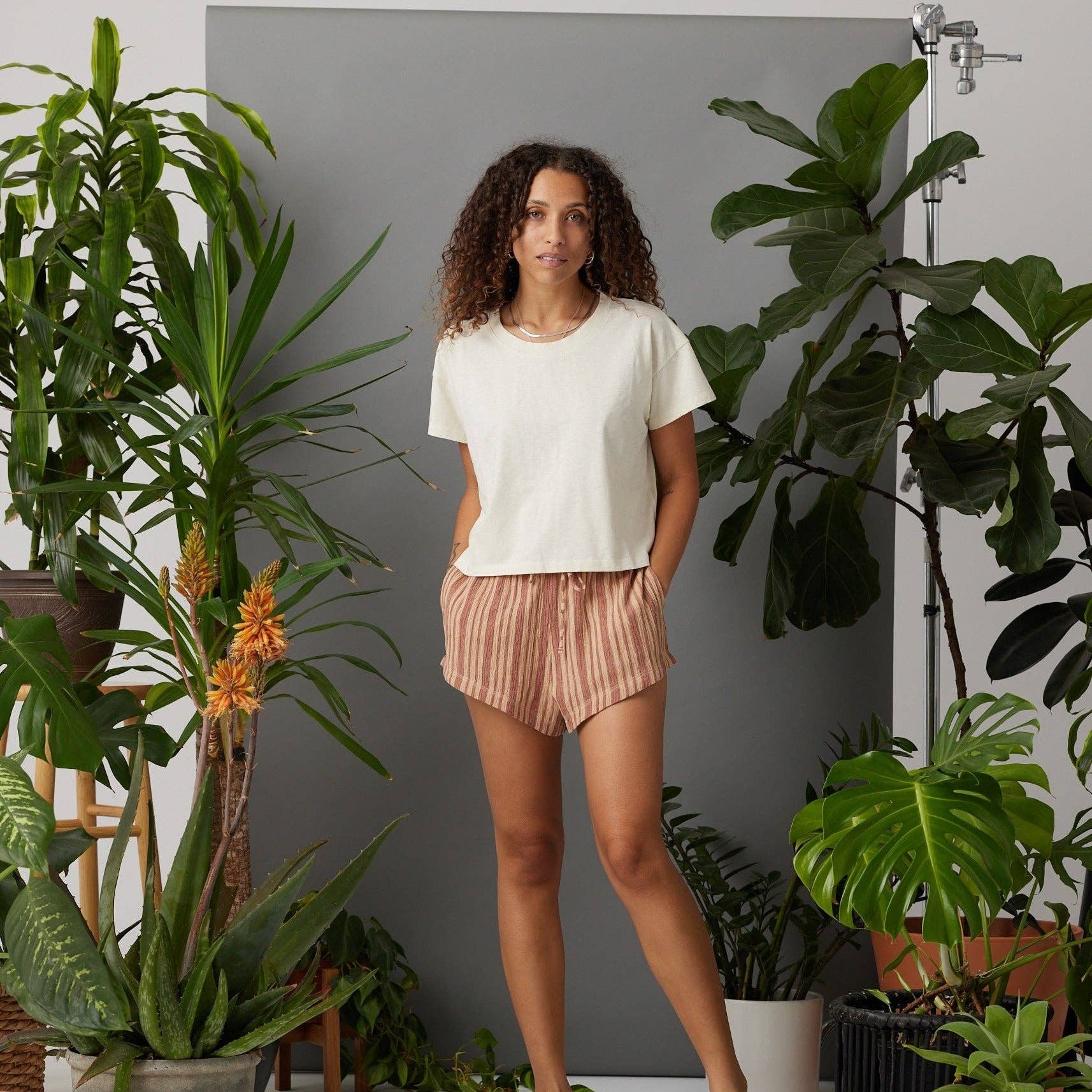 Woman standing among potted plants in a home setting