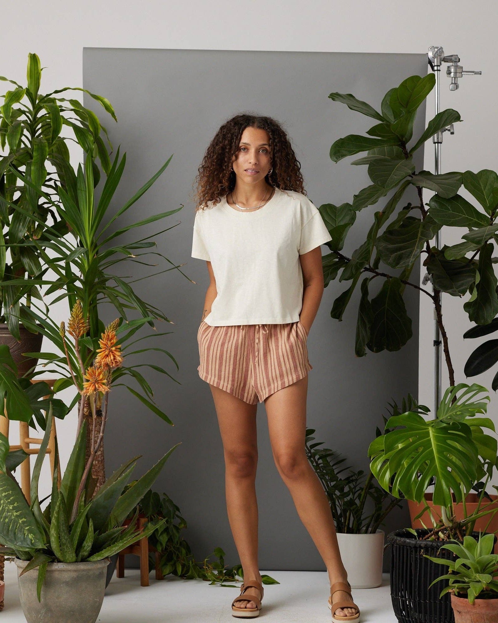 Woman standing among potted plants in a home setting