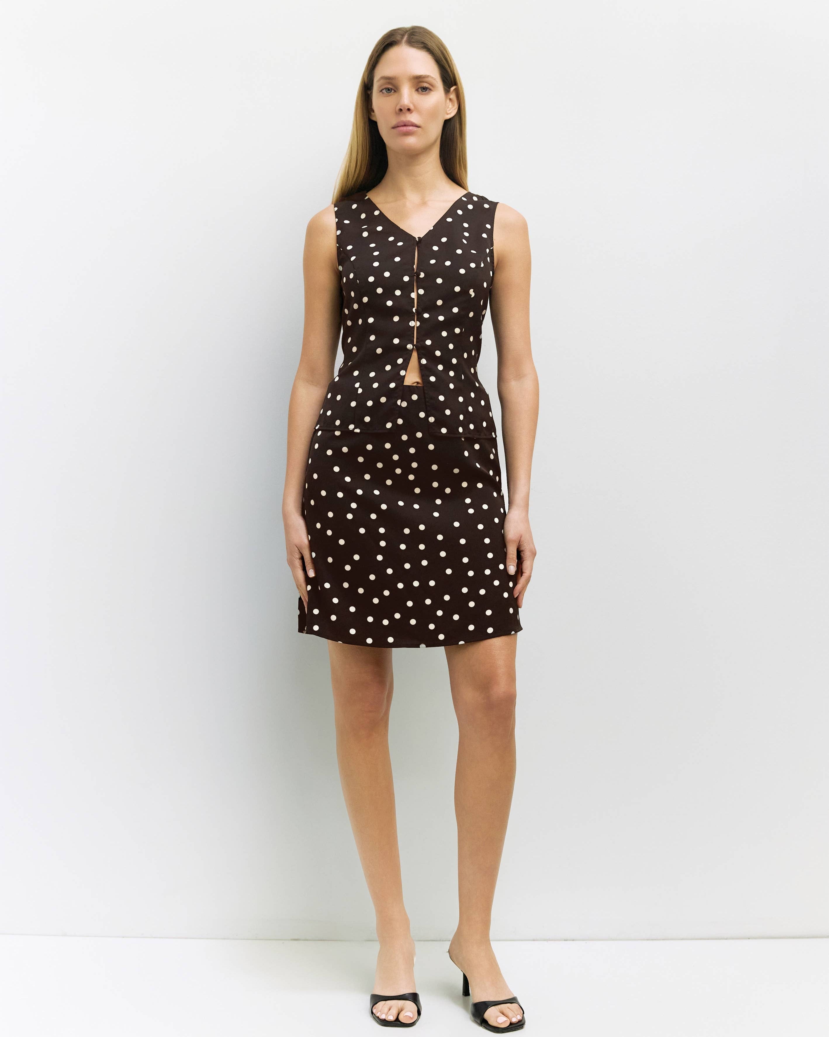 Woman wearing a brown top and skirt with white polka dots against a white background