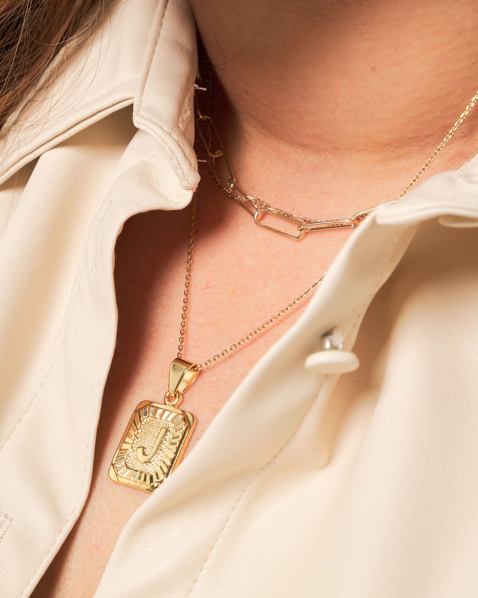 Woman wearing a letter J tarnish free gold initial charm necklace with a gold chain necklace.