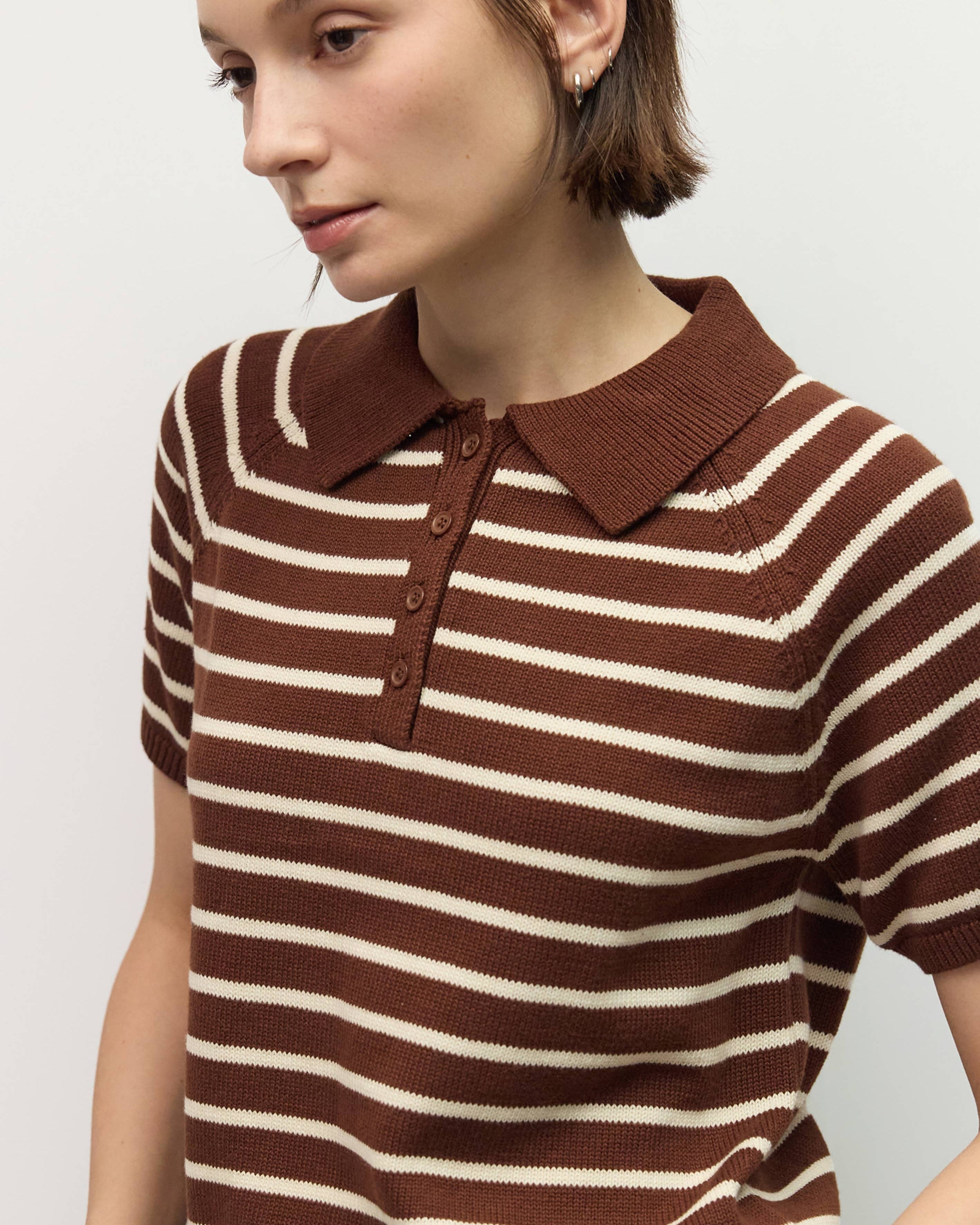 Woman wearing a brown and white striped sweater with a collar on a light gray background