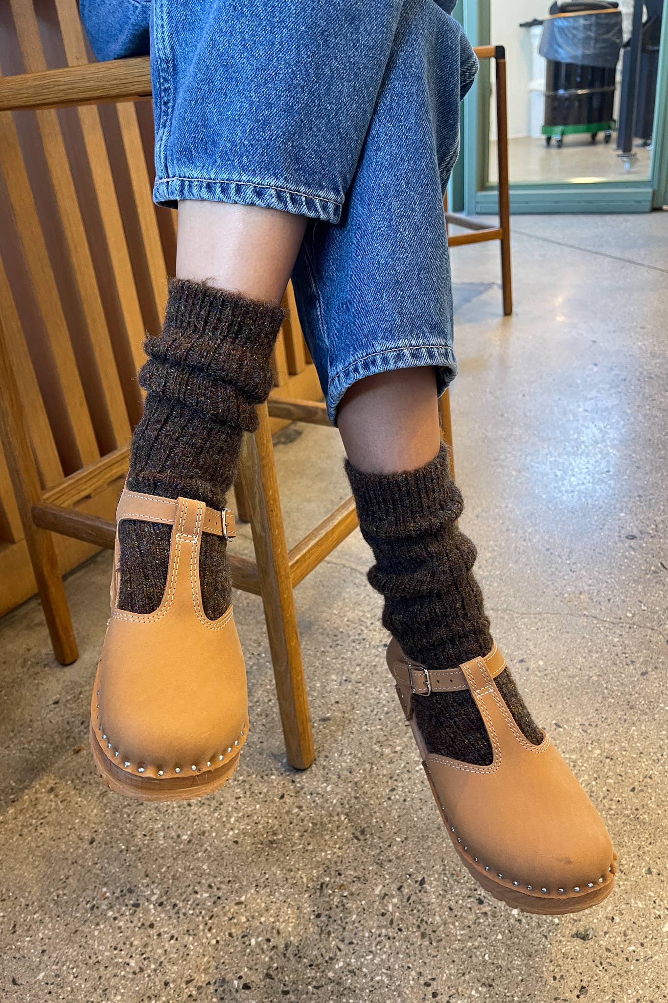 Person wearing beige boots with brown socks sitting on a chair.
