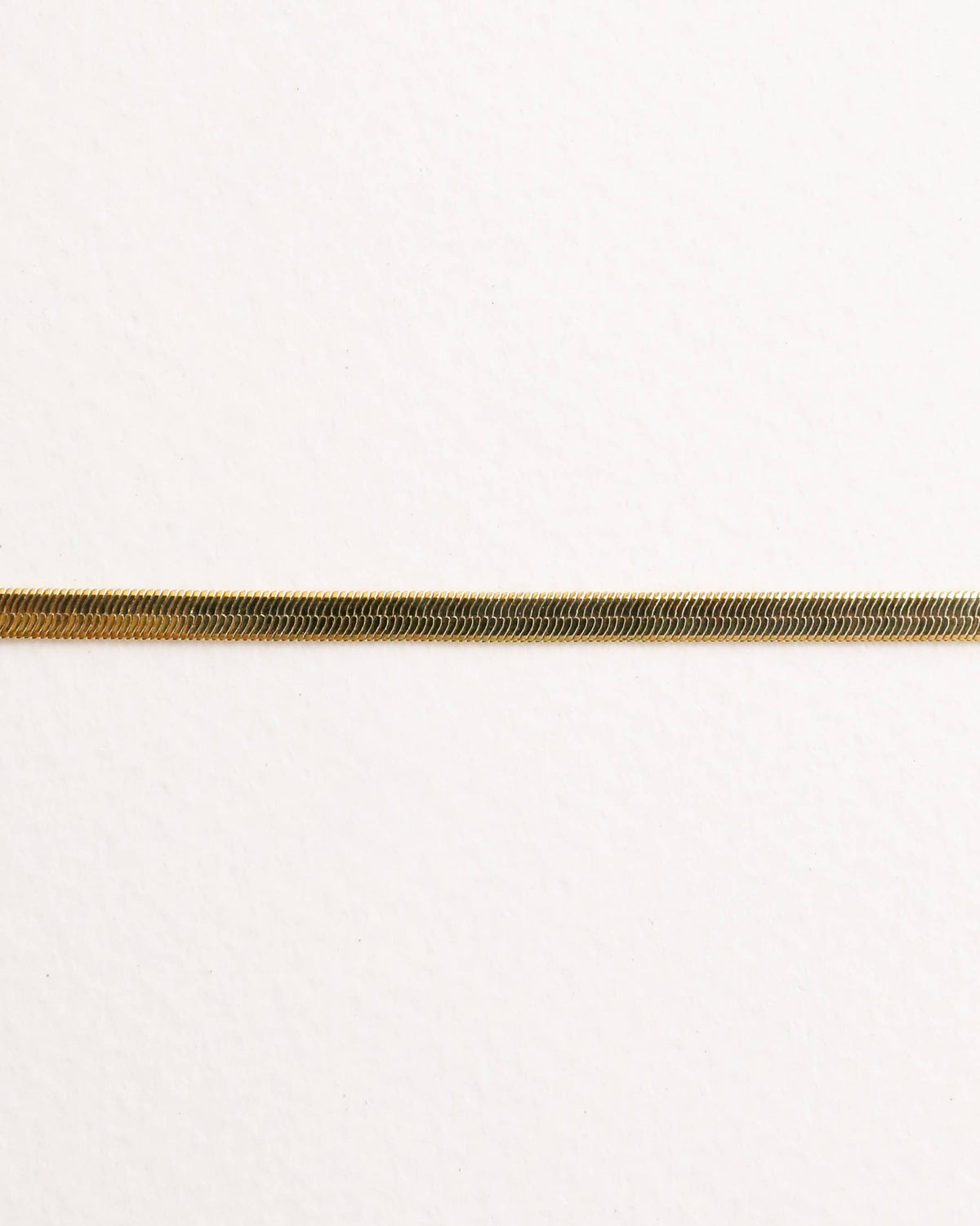 Close up of a gold bracelet on a white background