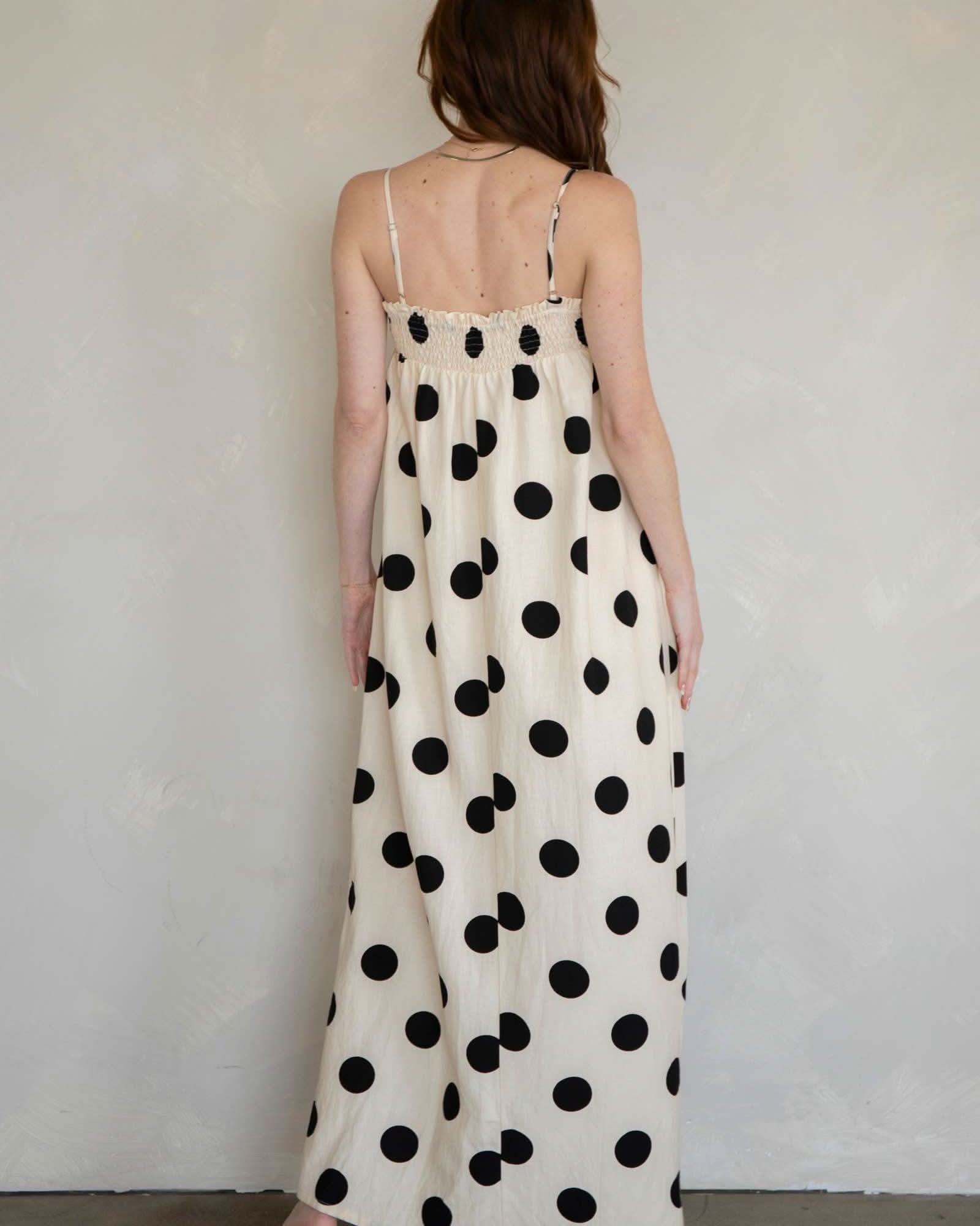 Woman wearing a polka dot dress against a plain background