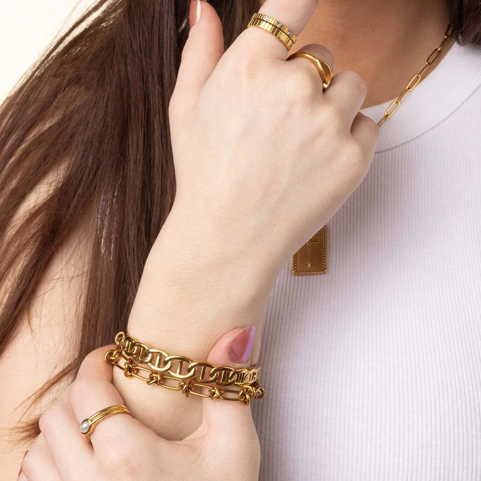 Close-up of a person's hand wearing gold jewelry on a white background