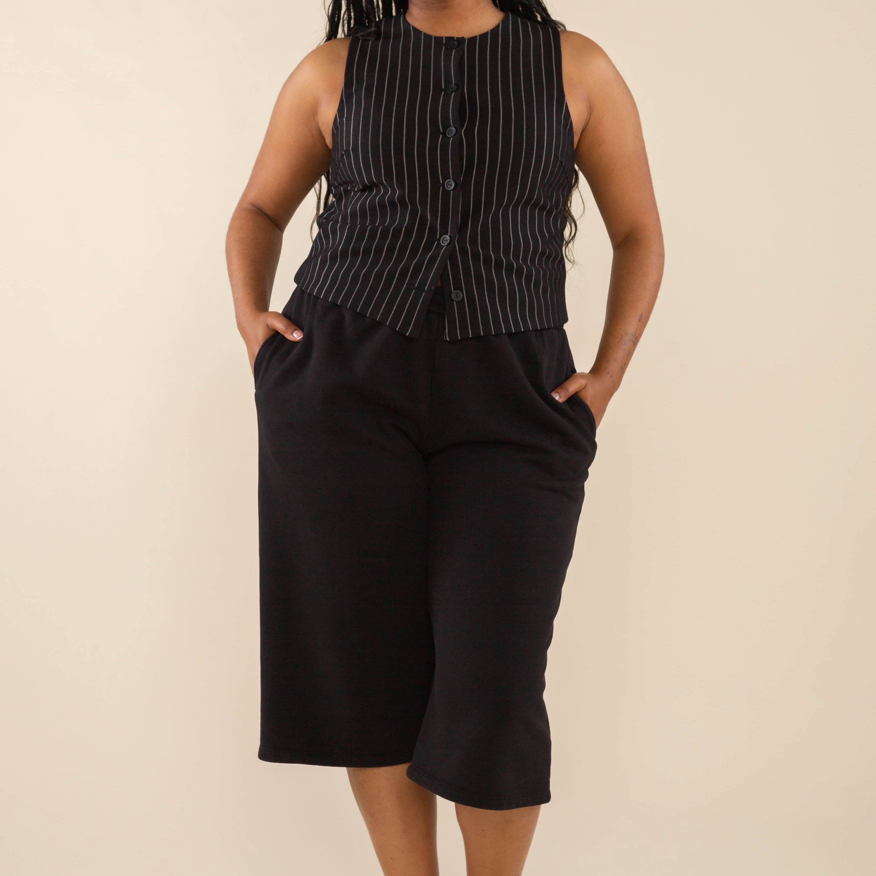 Woman wearing black high neck vest with cream pinstripes. Vest has black buttons all the way down