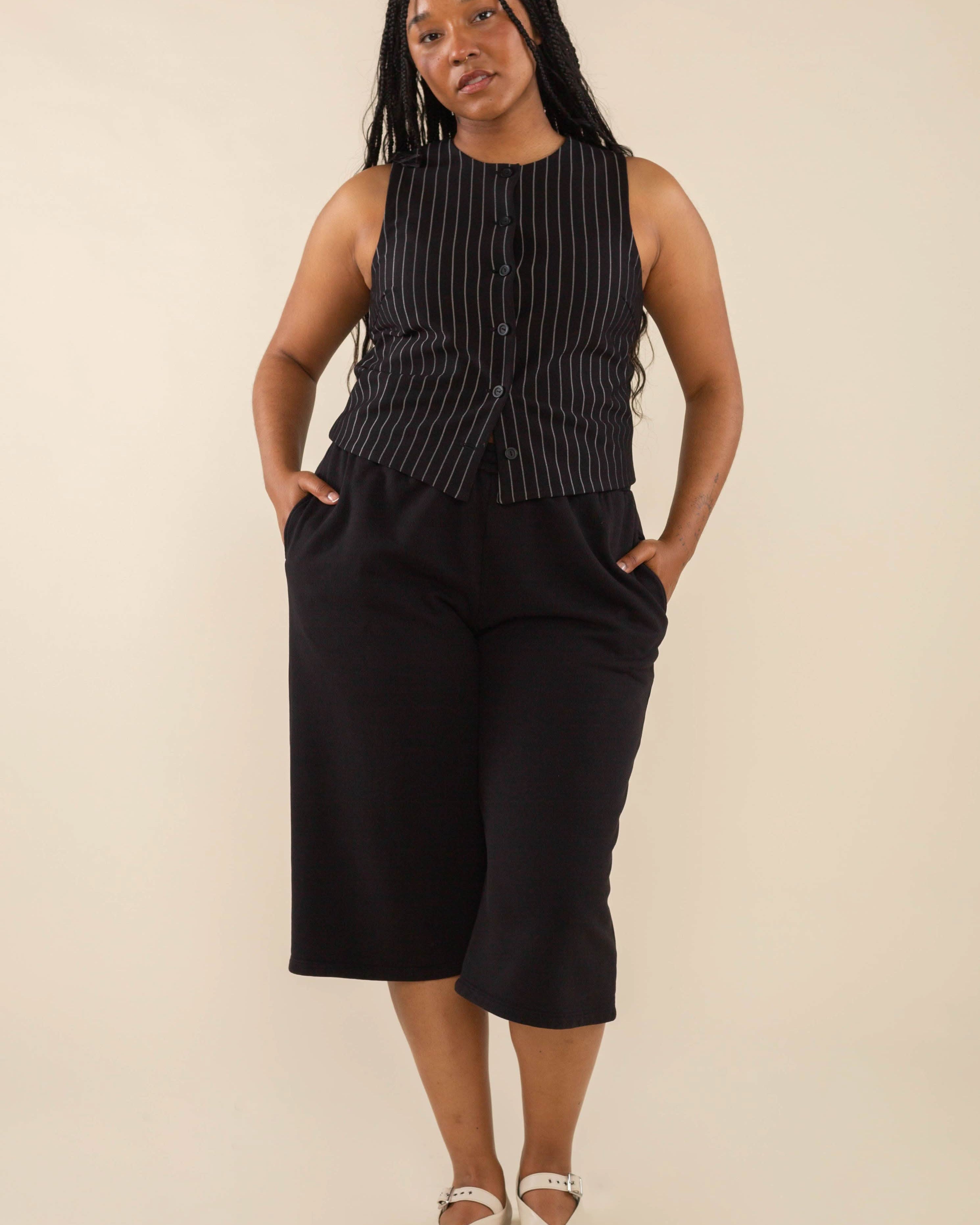 Woman wearing black high neck vest with cream pinstripes. Vest has black buttons all the way down