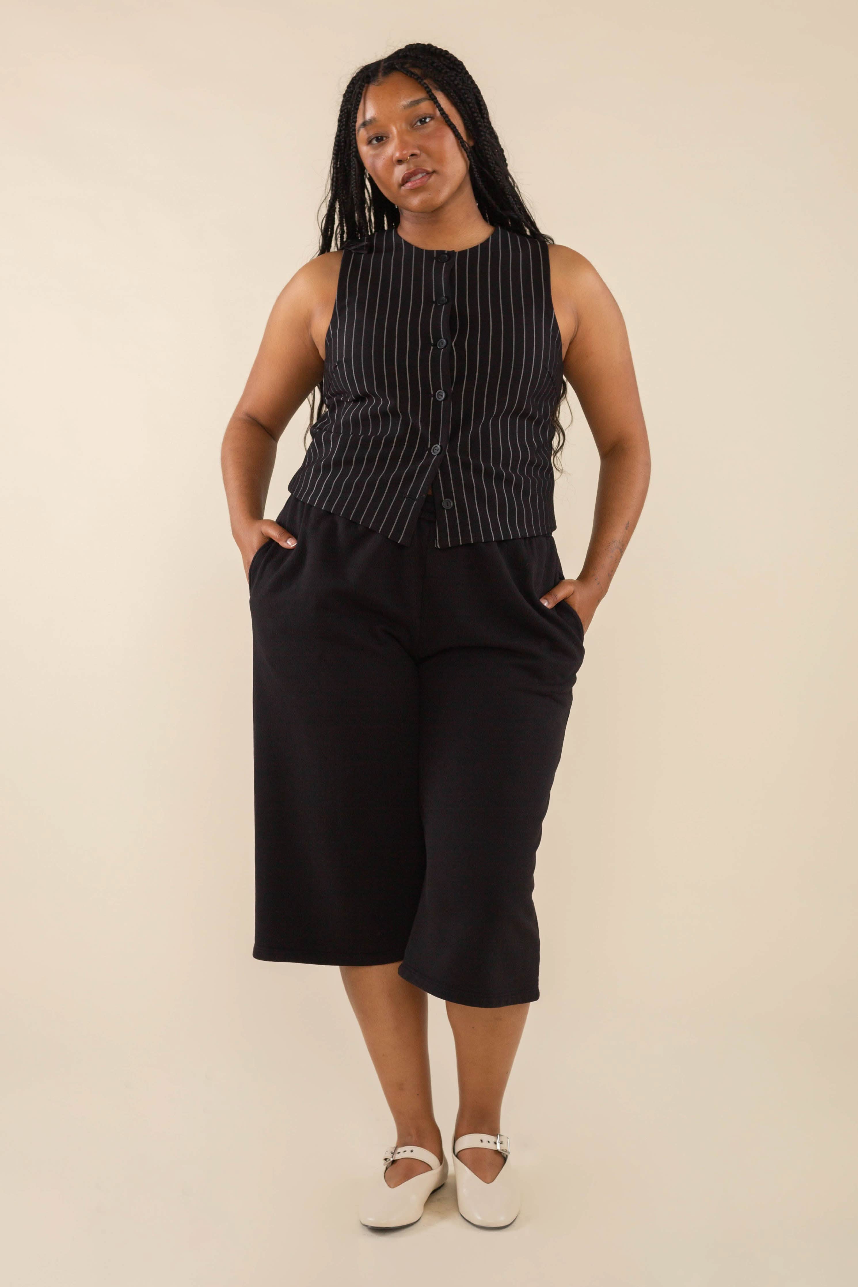 Woman wearing black high neck vest with cream pinstripes. Vest has black buttons all the way down