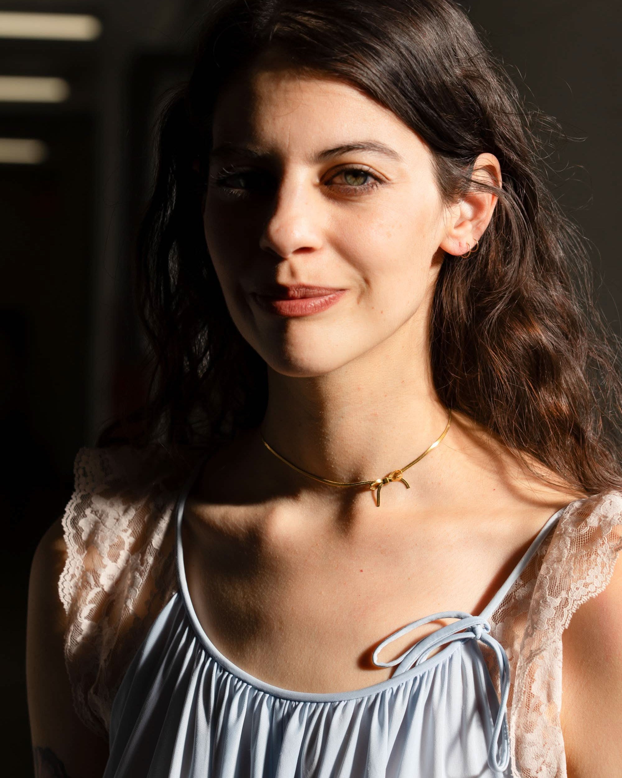 woman wearing gold bow chocker necklace