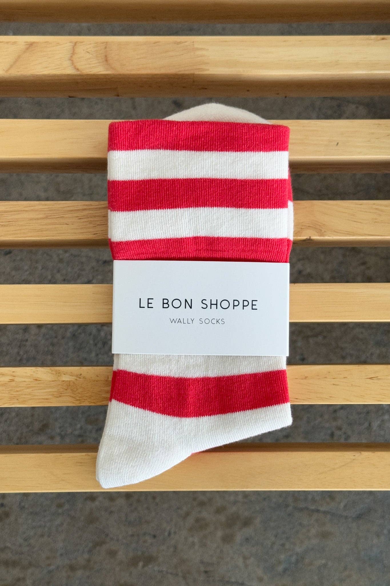 Red and white striped sock with 'Le Bon Shoppe' label on a wooden surface