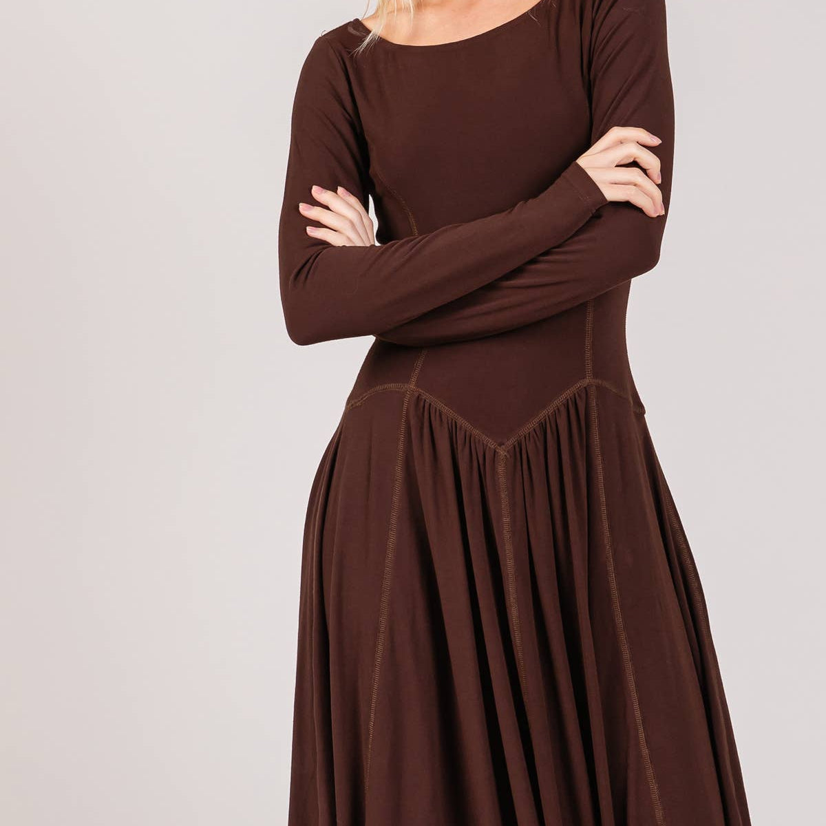 Woman wearing a brown long-sleeve dress against a plain background