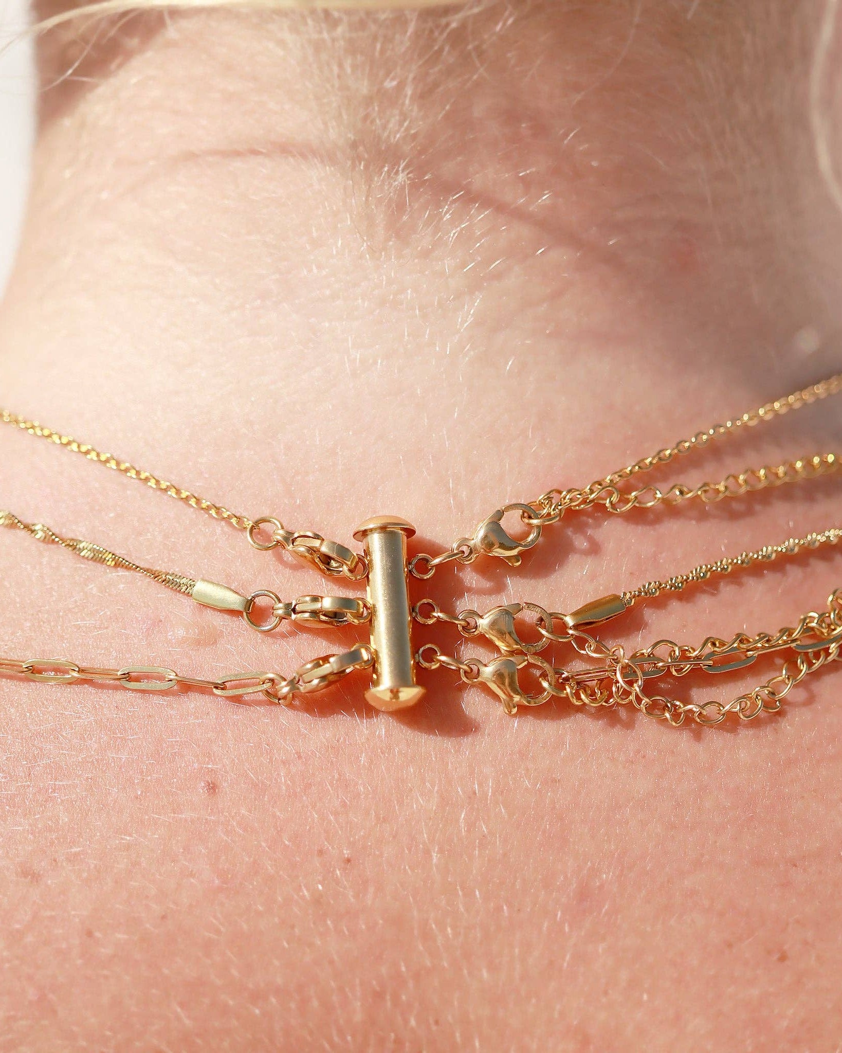Close-up of a person's wrist wearing multiple gold bracelets.