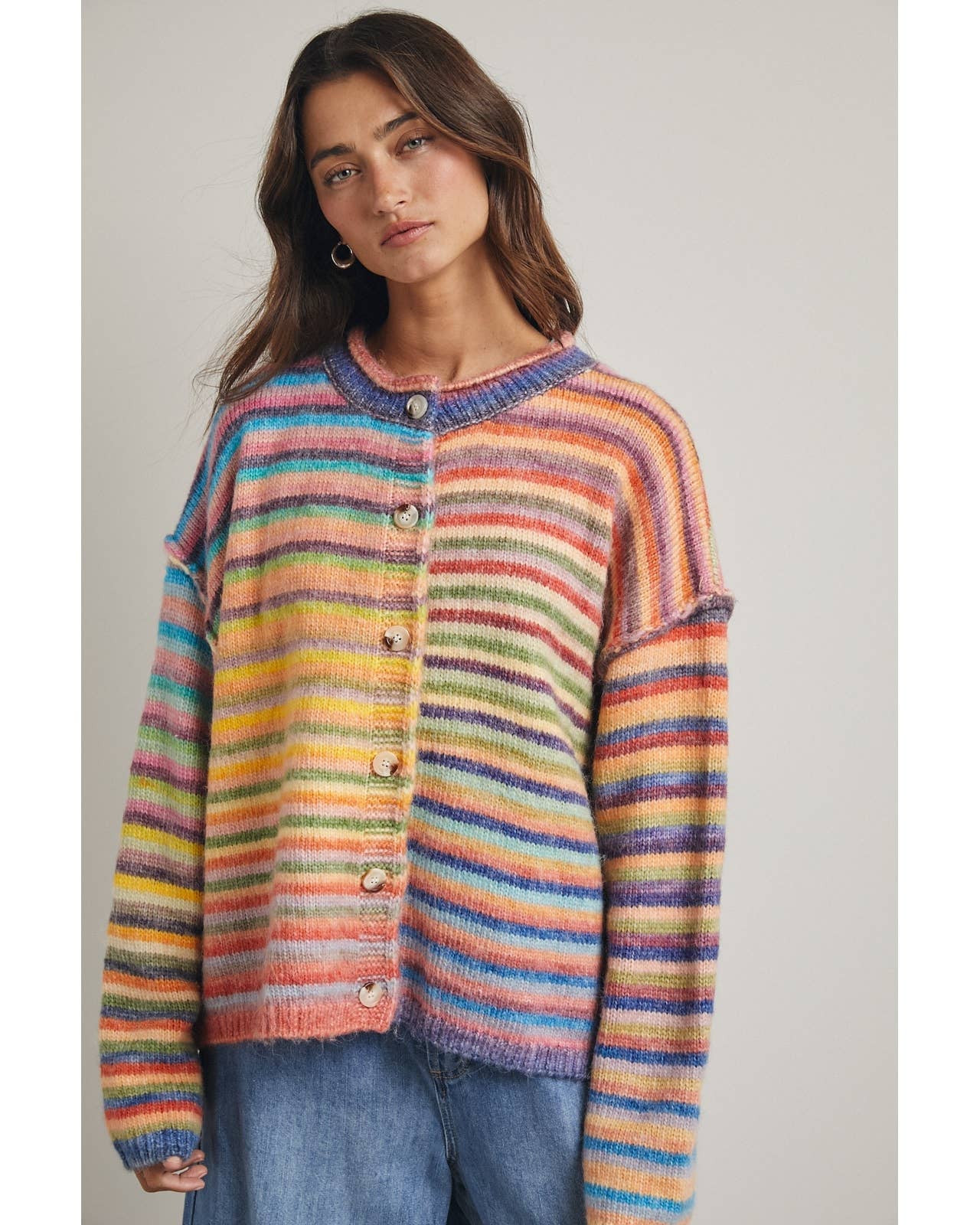 Woman wearing a colorful striped sweater against a plain background