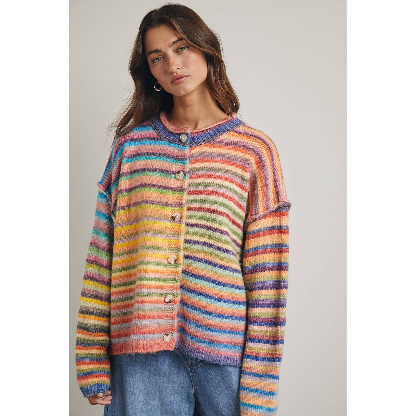 Woman wearing a colorful striped sweater against a plain background