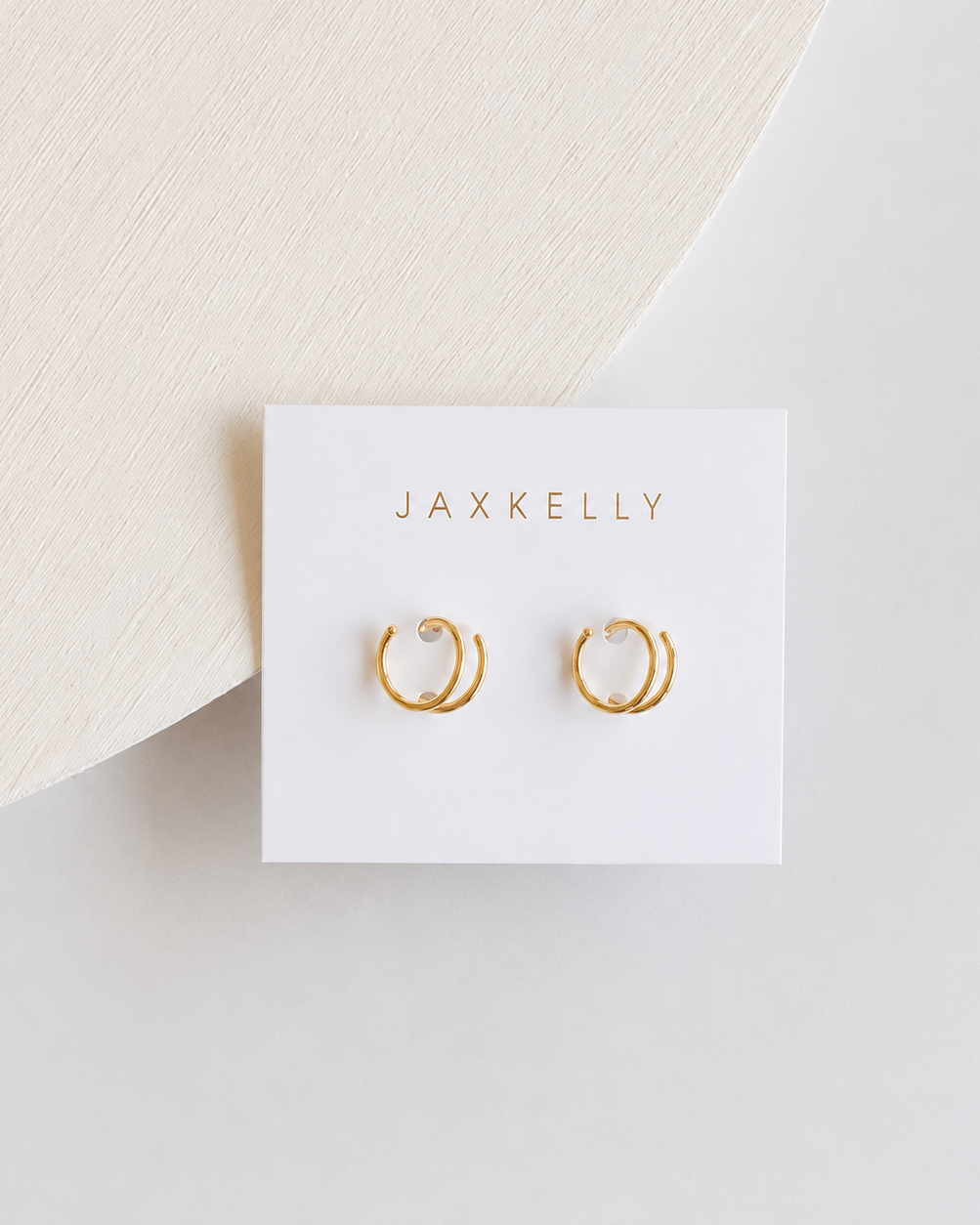 Gold hoop spiral earrings on a Jaxkelly branded card against a light background