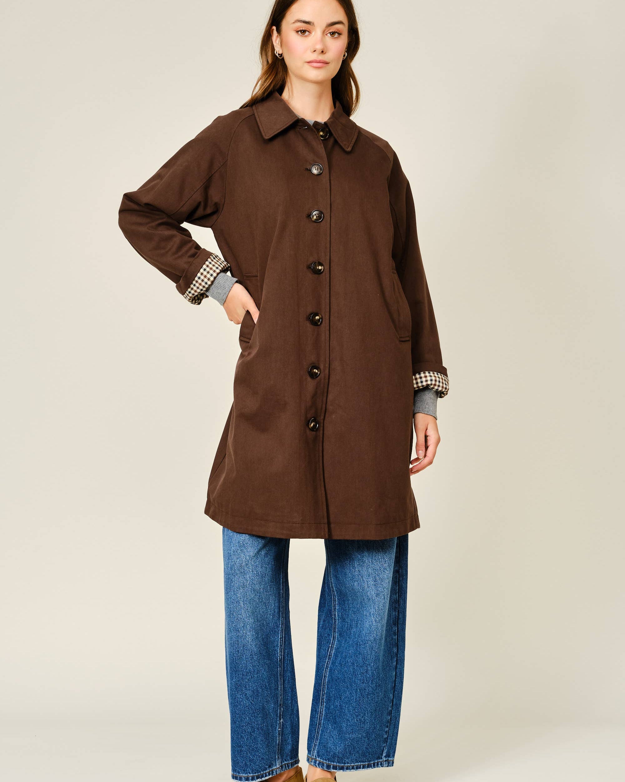 Woman wearing a brown coat with a plain background