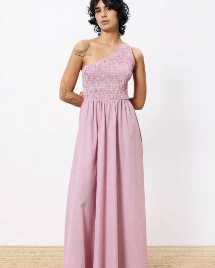 Woman wearing a pink one-shoulder dress against a white background