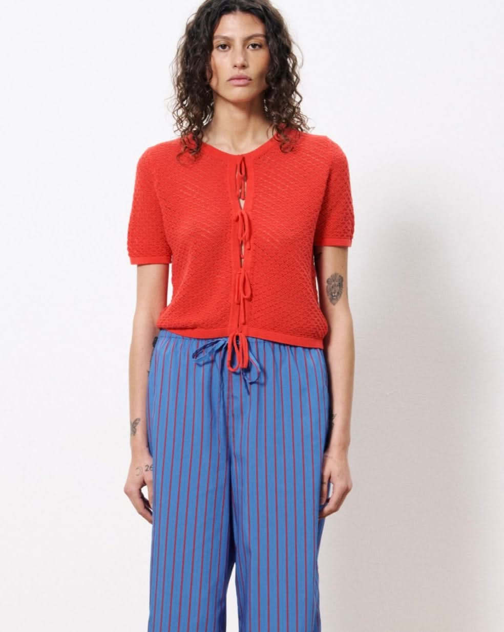 Woman wearing red top and blue pants with red vertical stripes all over