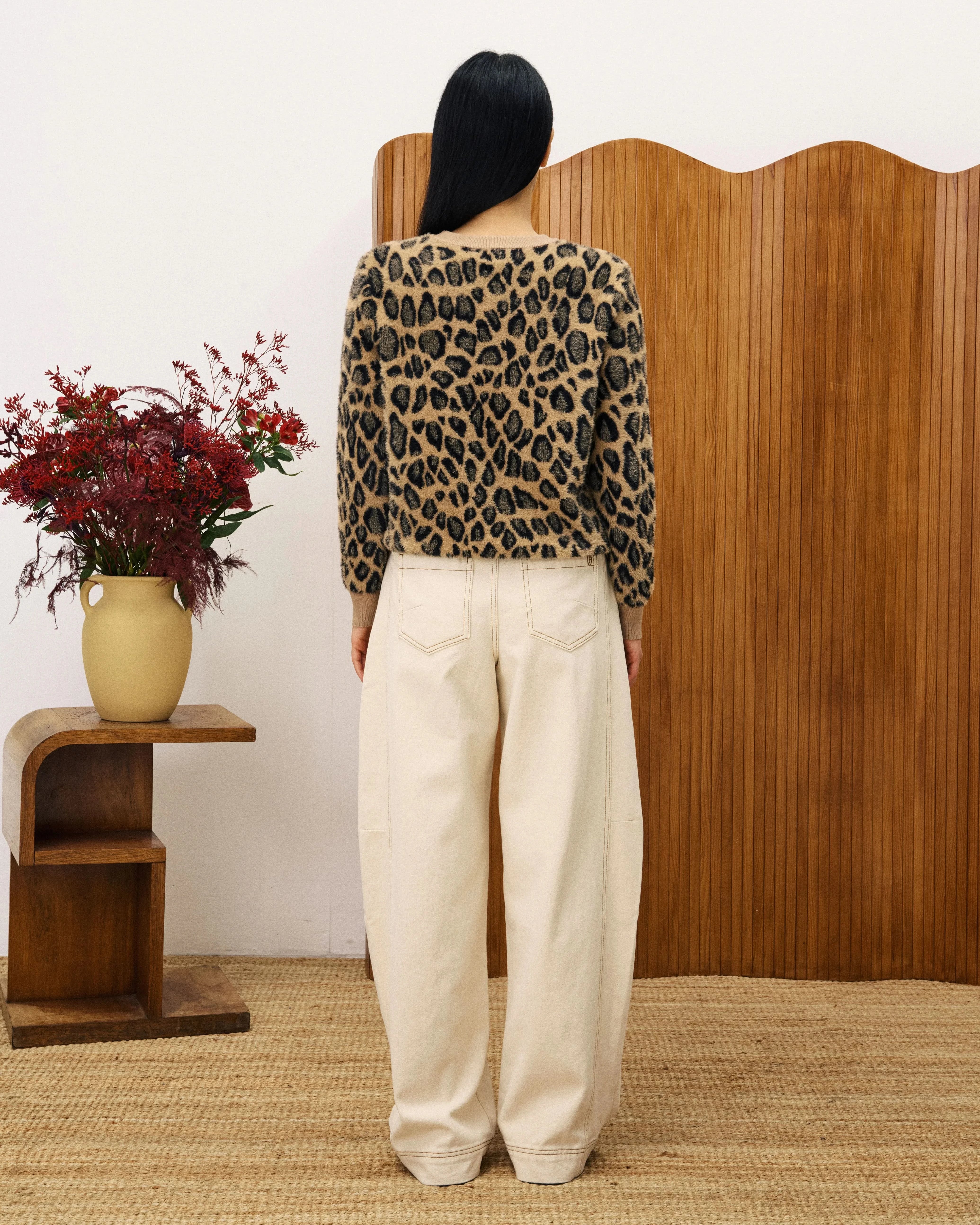 Person wearing a leopard print top and white pants standing