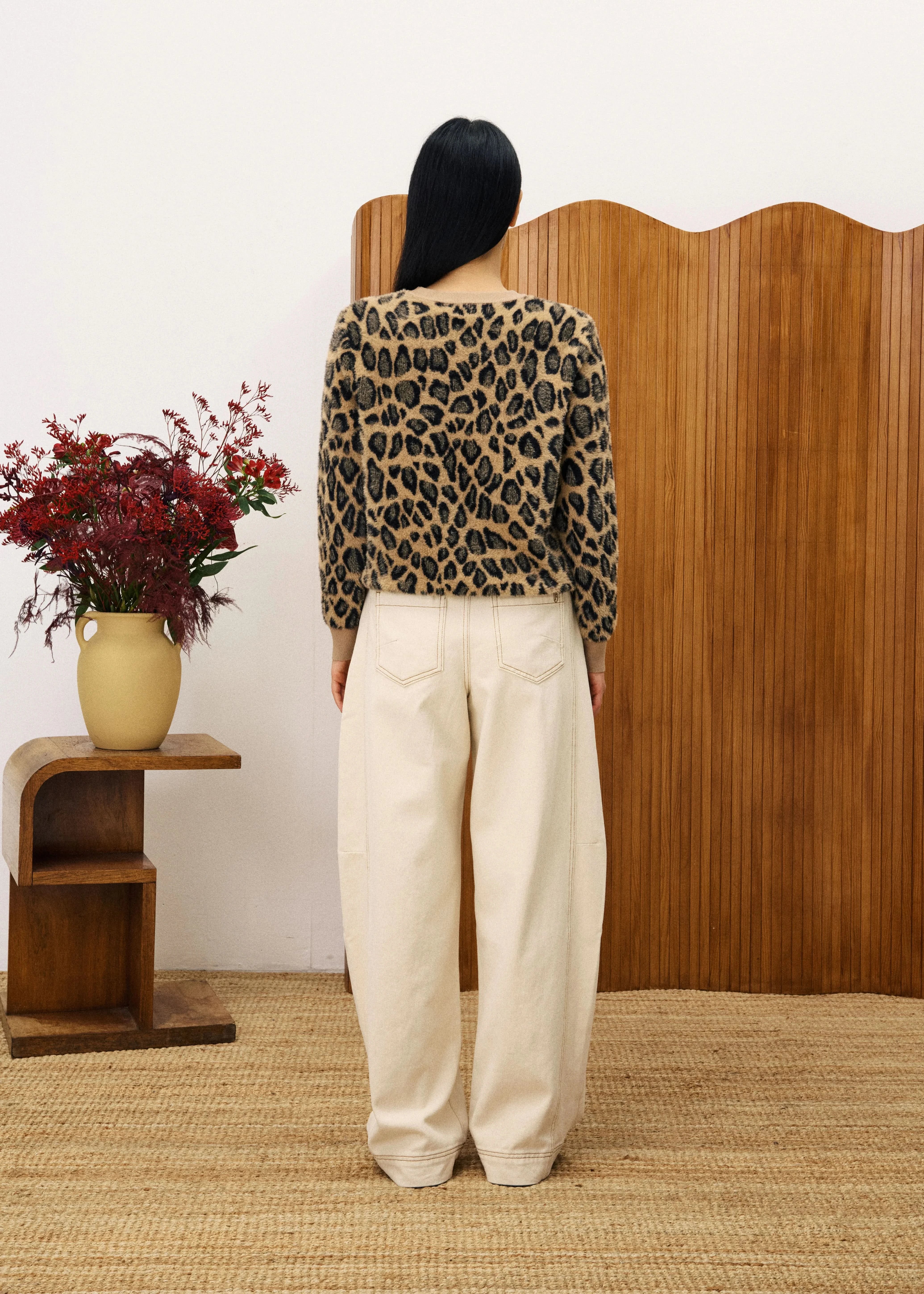 Person wearing a leopard print top and white pants standing