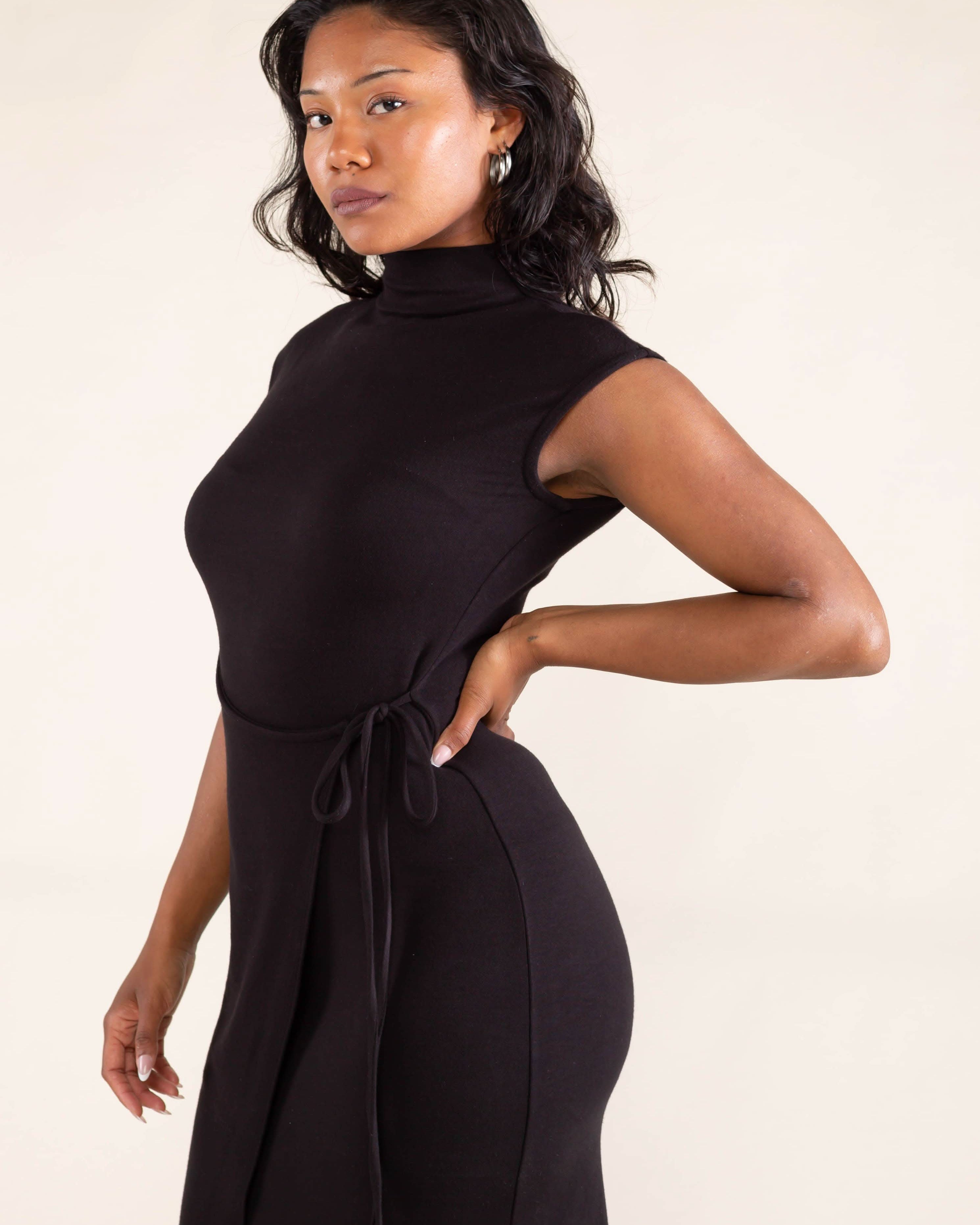 Woman wearing a black sleeveless dress against a beige background