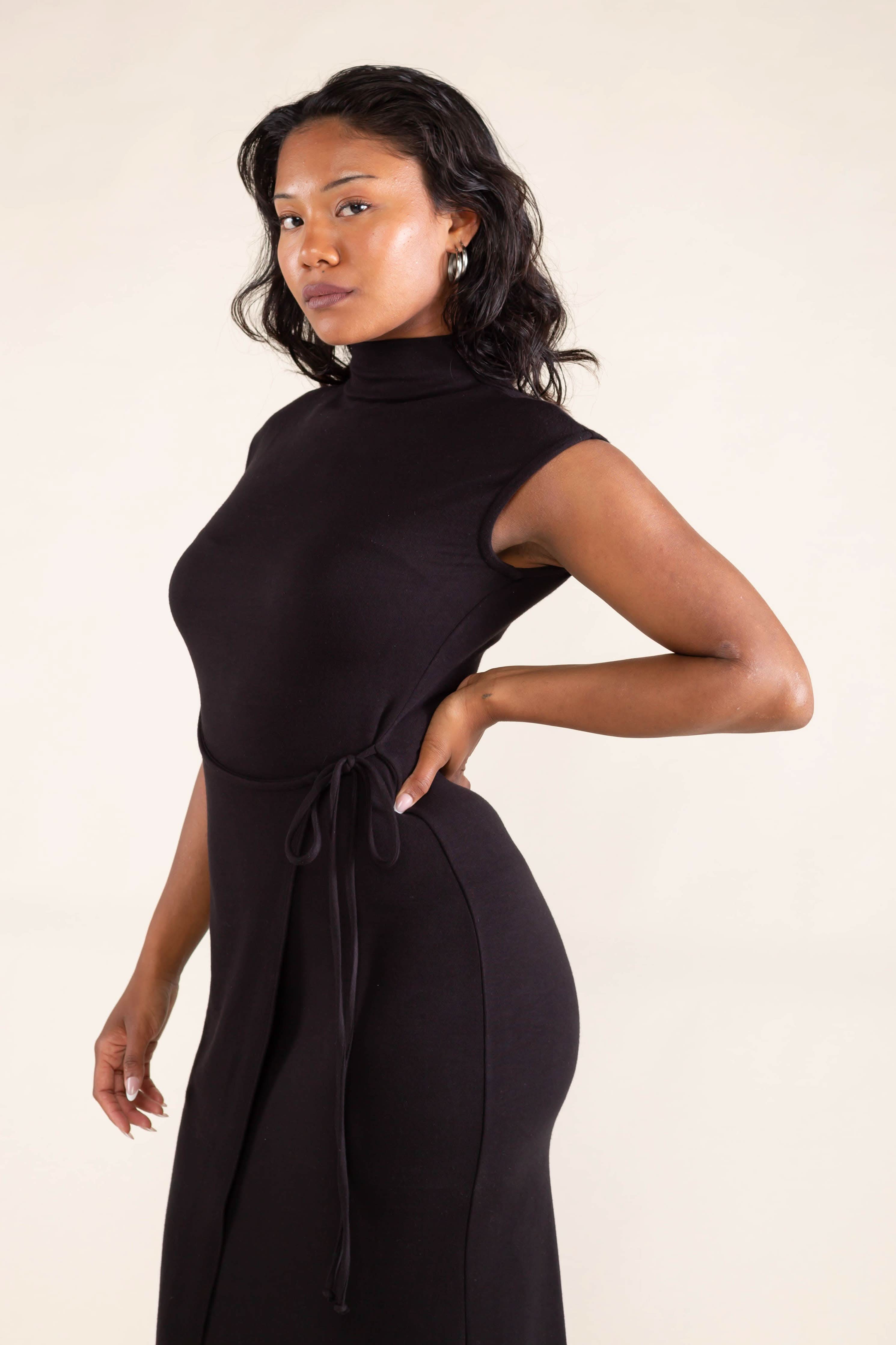 Woman wearing a black sleeveless dress against a beige background