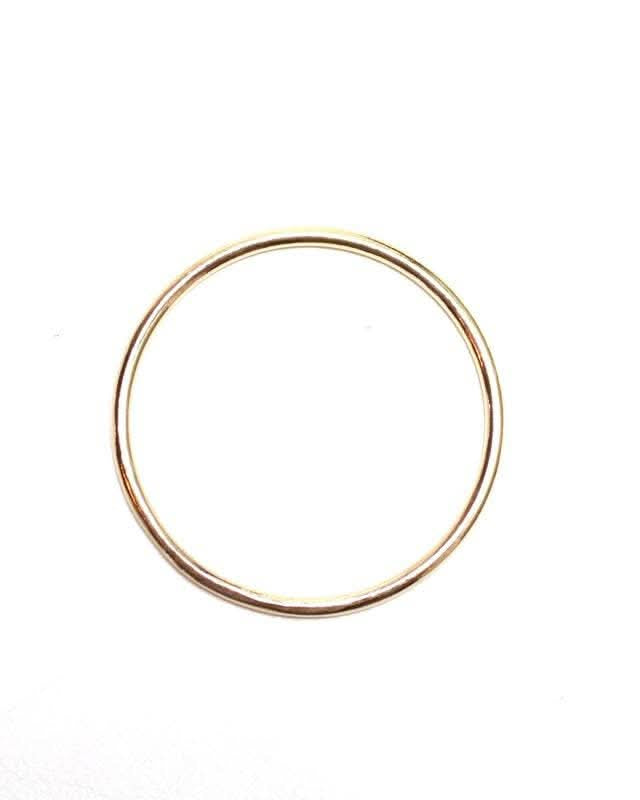 Simple thin gold ring for stacking laying on a white background