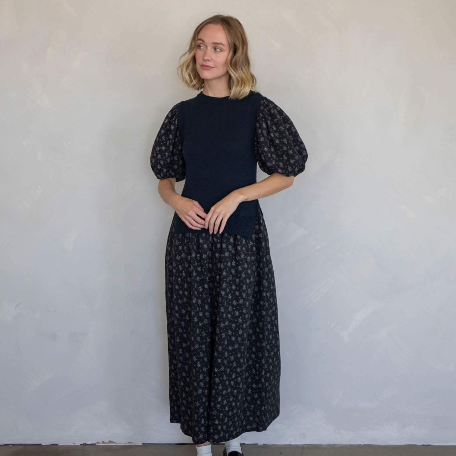 Keri Floral Sweater Vest Dress Woman wearing a black dress with puff sleeves