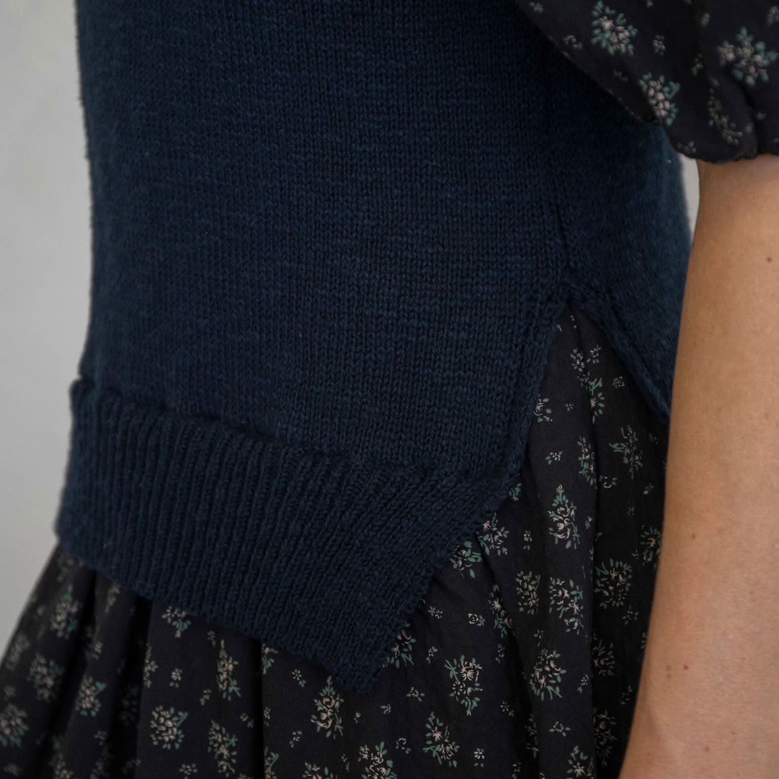 Navy blue knitted cardigan over a patterned dress on a neutral background
