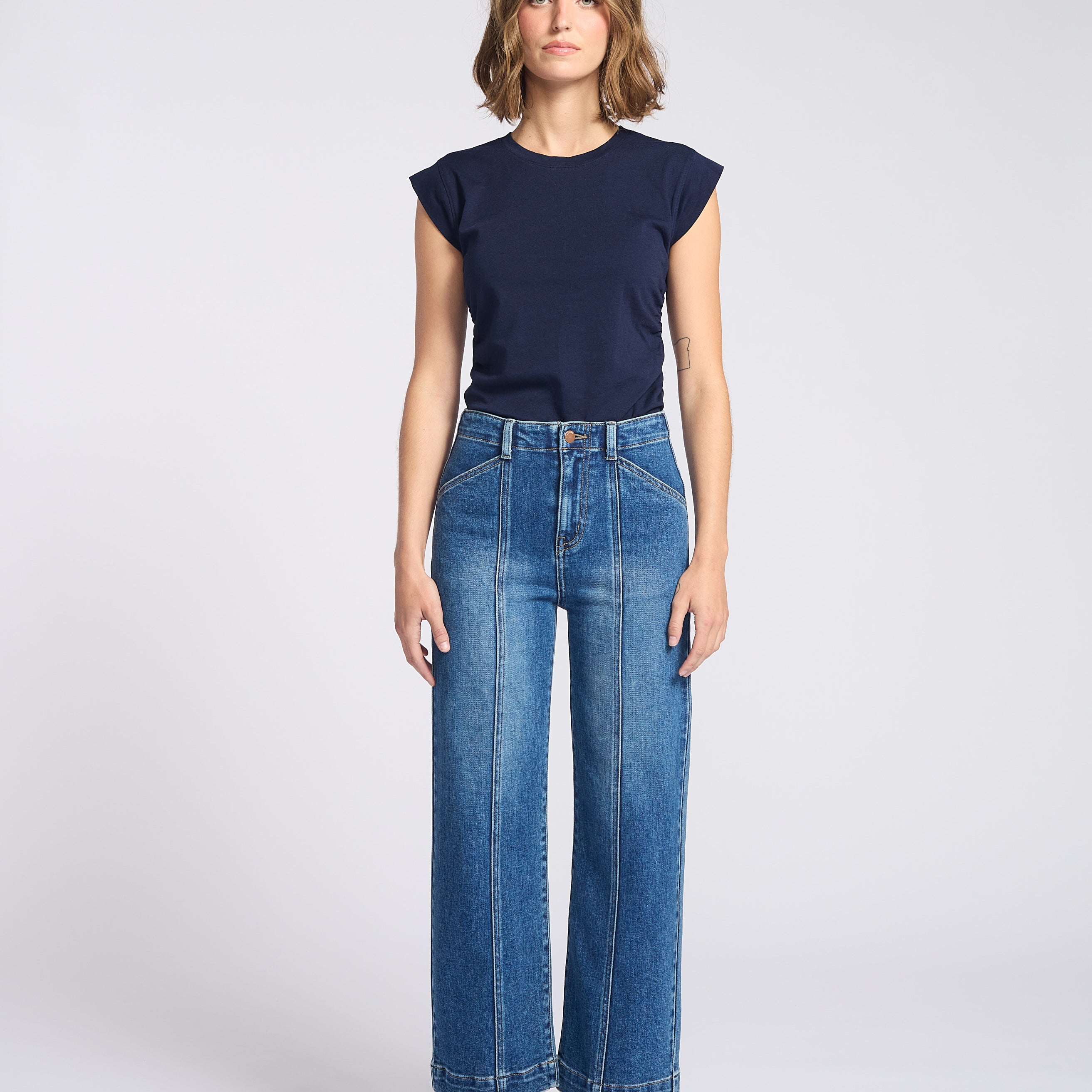 Dark jeans with seam down the front of each pant leg with navy blue shirt