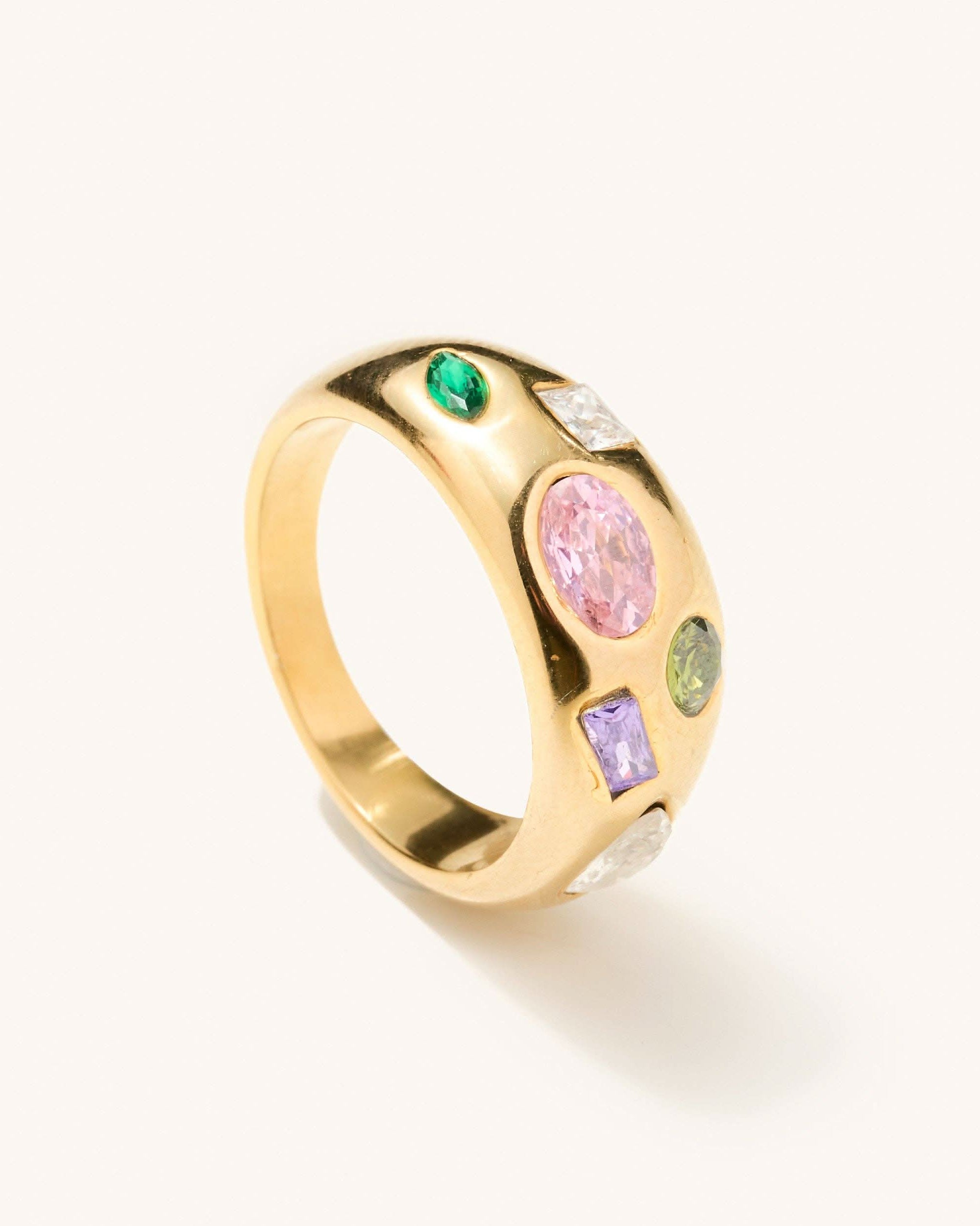 Gold ring with multi shaped and colored gems across the thickest head of the ring