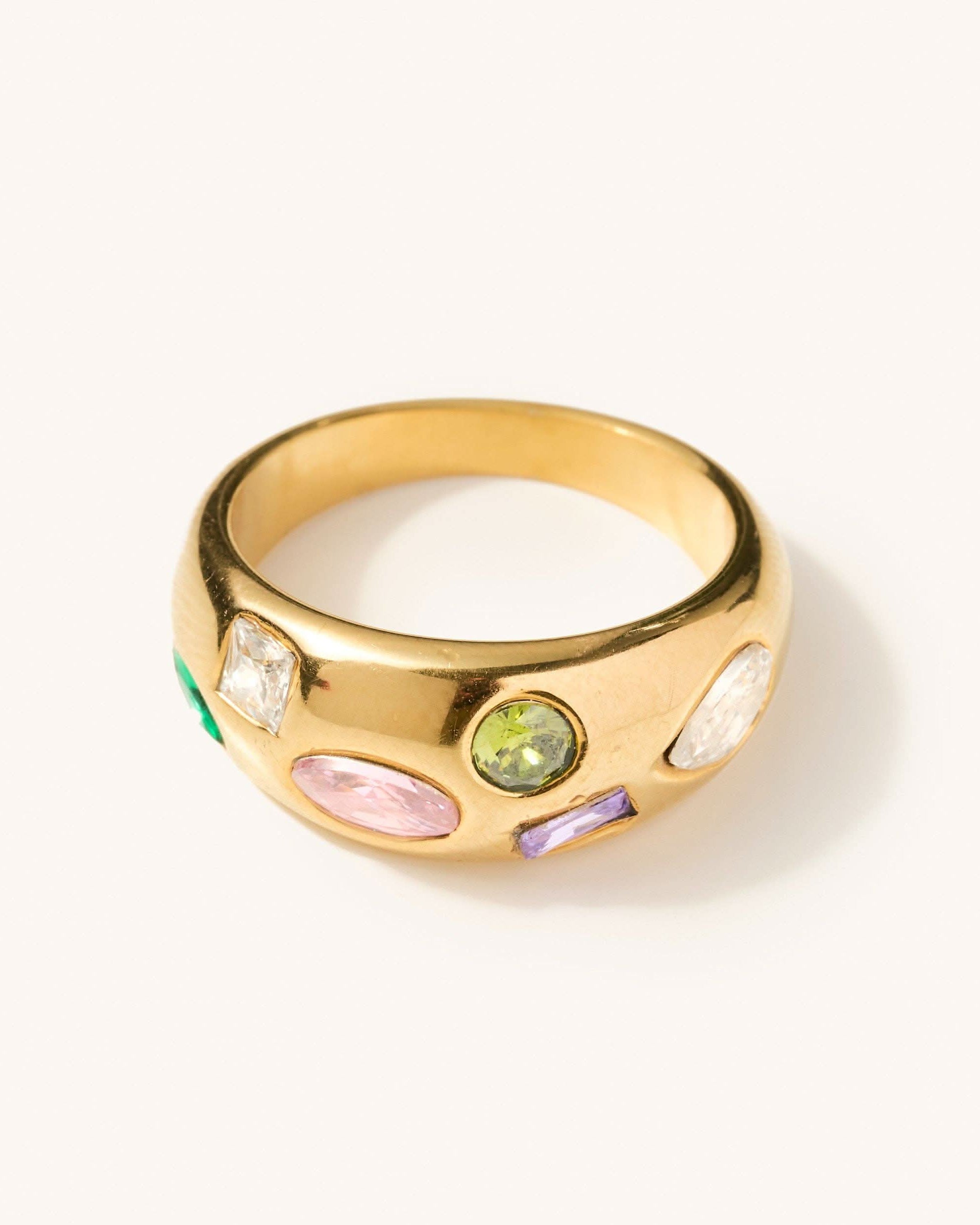 Gold ring with multi shaped and colored gems across the thickest head of the ring