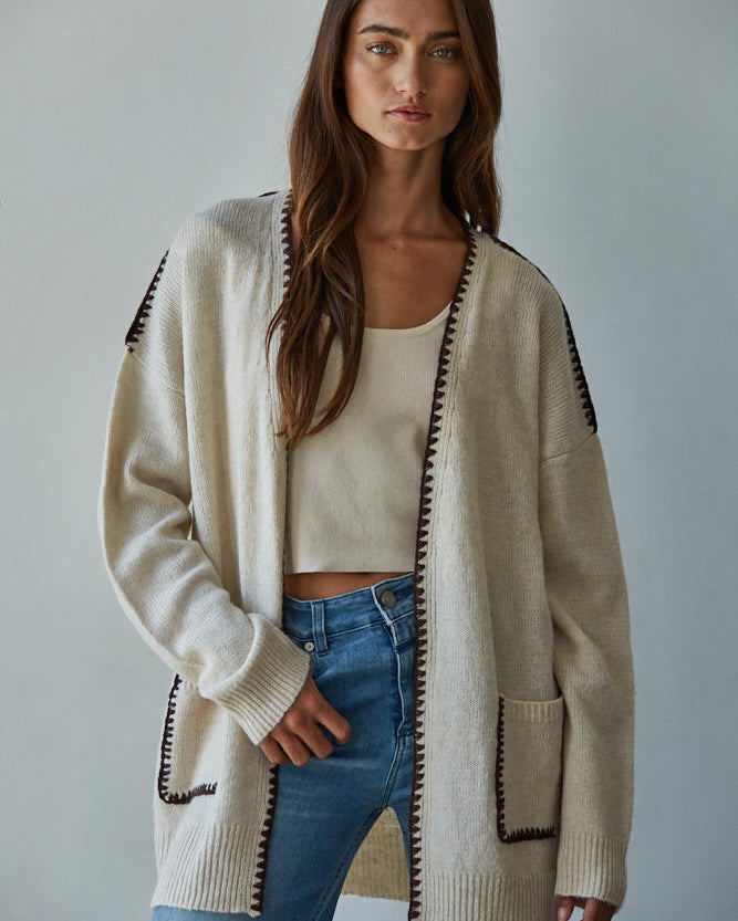 Woman wearing a Lotte Contrast Stitch Open Cardigan with black trim, white top