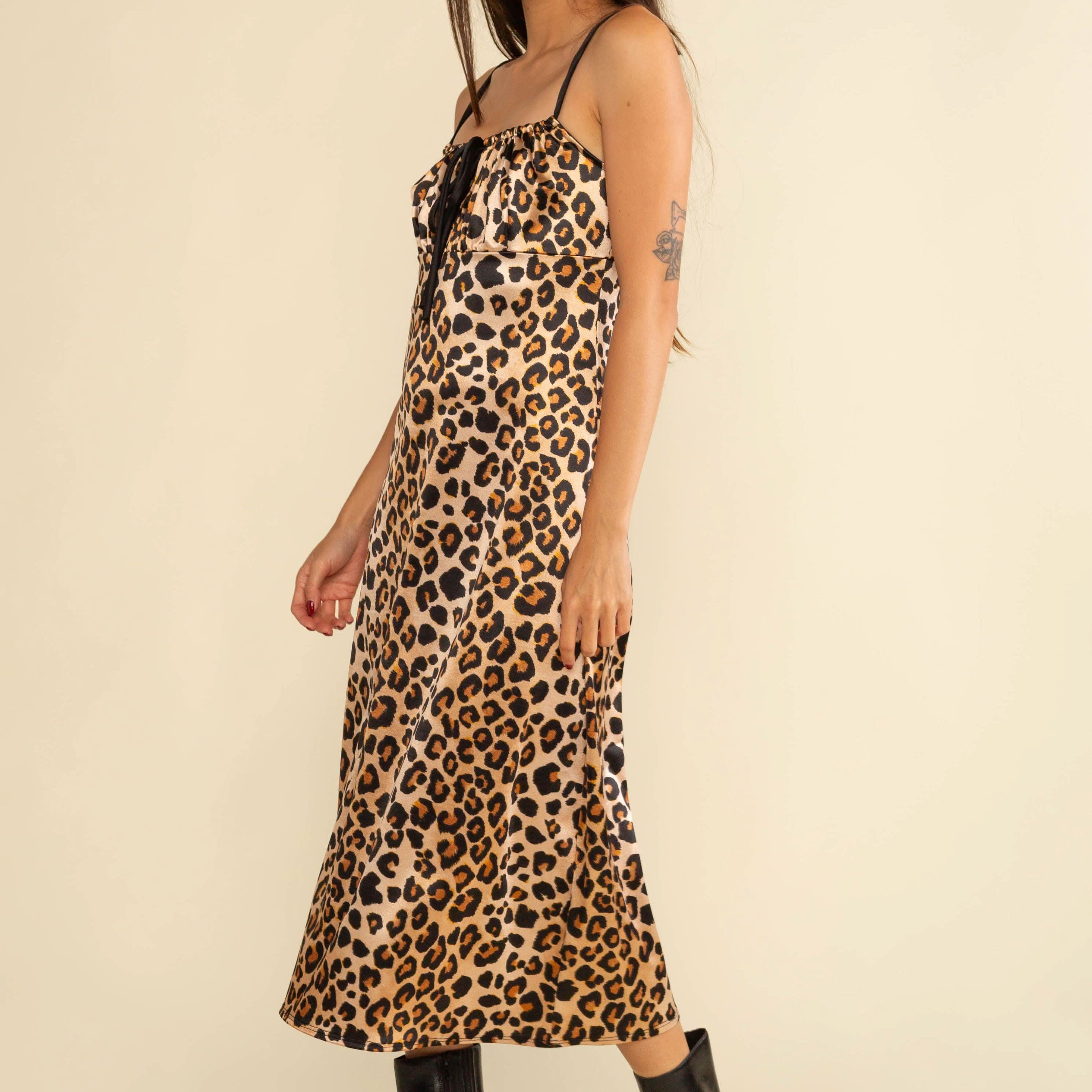 Woman wearing a leopard print dress with black boots on a beige background